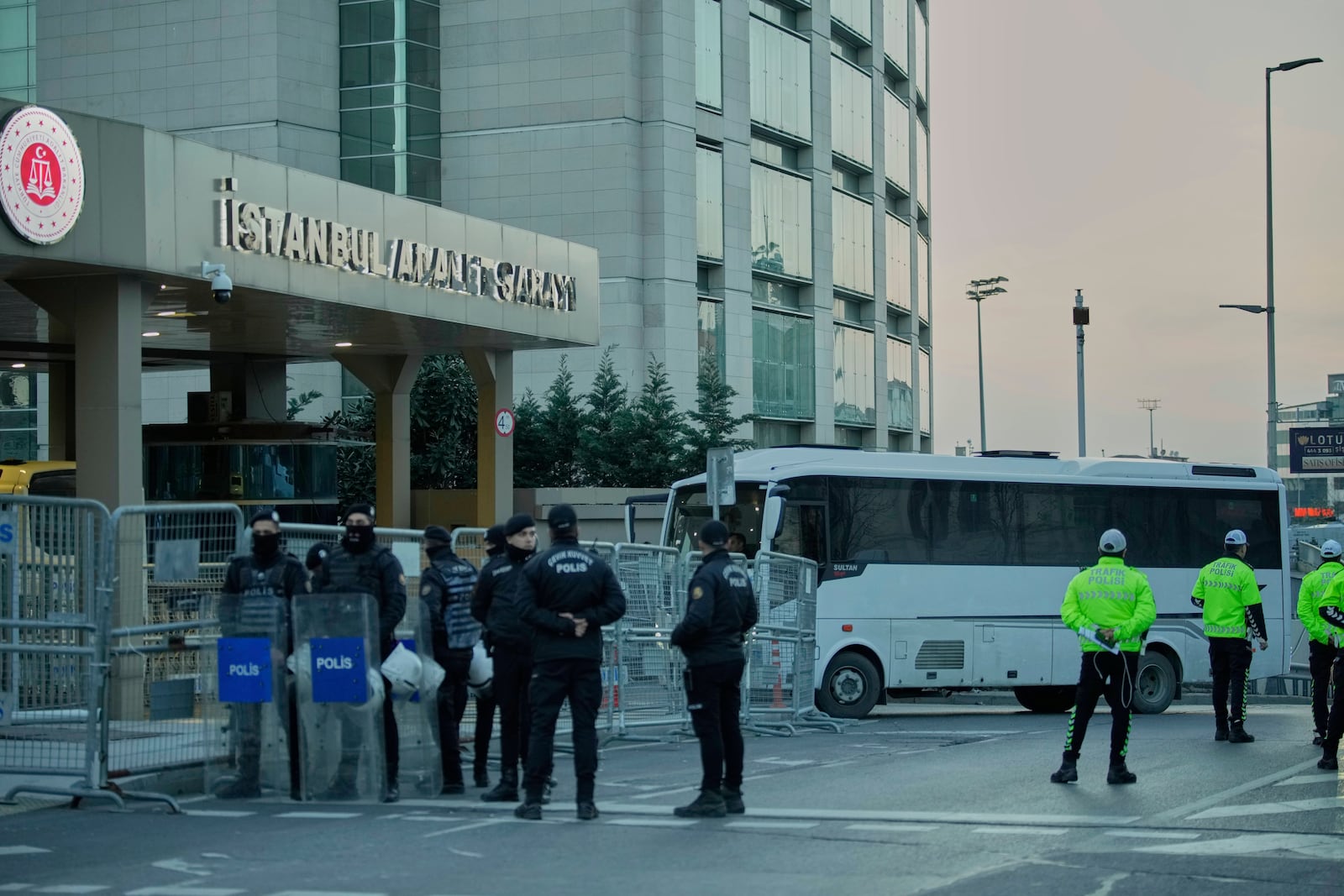 Policemen stand guard next to a police bus carrying Istanbul's Mayor Ekrem Imamoglu and other arrested to Caglayan courthouse, as protesters protest against their arrest, outside Caglayan courthouse, in Istanbul, Turkey, Saturday, March 22, 2025. (AP Photo/Emrah Gurel)