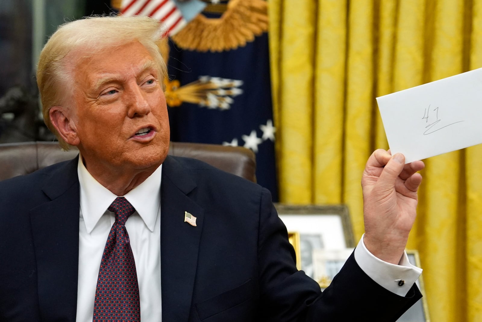 President Donald Trump holds a letter that former President Joe Biden left for him as signs executive orders in the Oval Office of the White House, Monday, Jan. 20, 2025, in Washington. (AP Photo/Evan Vucci)