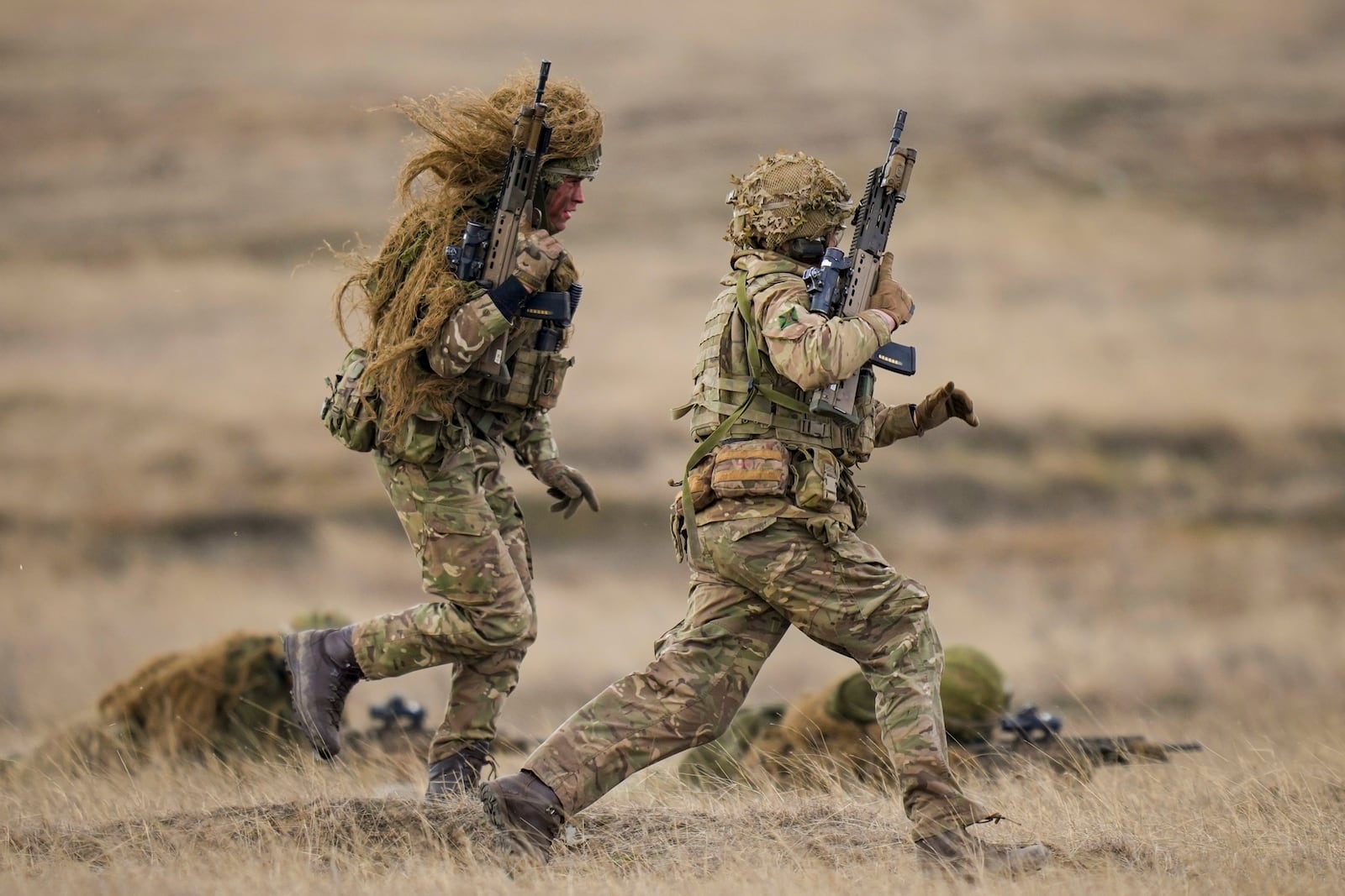 Servicemen run to a position during the Steadfast Dart 2025 exercise, involving some 10,000 troops in three different countries from nine nations and represent the largest NATO operation planned this year, at a training range in Smardan, eastern Romania, Wednesday, Feb. 19, 2025. (AP Photo/Vadim Ghirda)