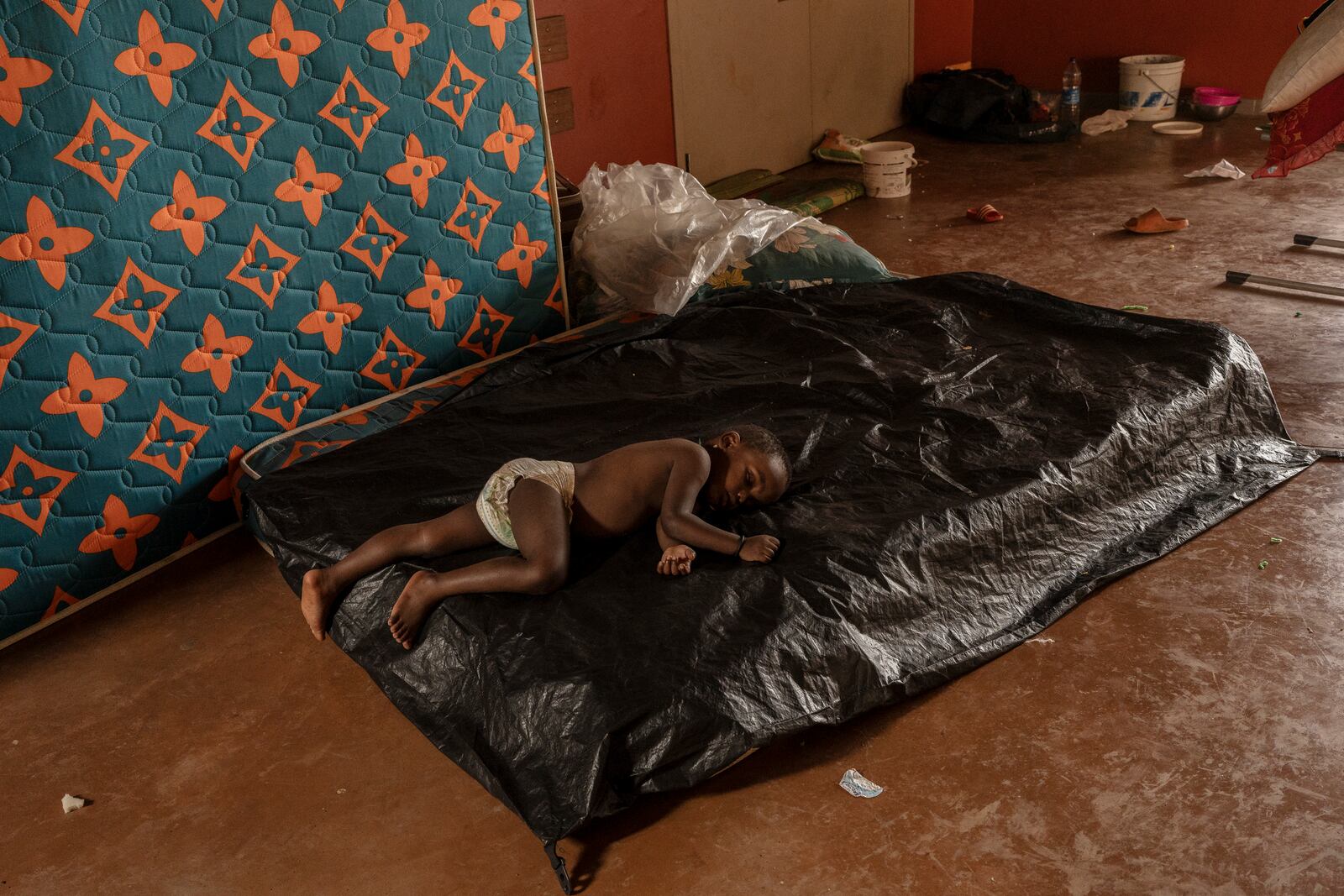 A child sleeps at the Lycée des Lumières where he found refuge, Thursday, Dec. 19, 2024 in Mamoudzou, Mayotte, (AP Photo/Adrienne Surprenant)