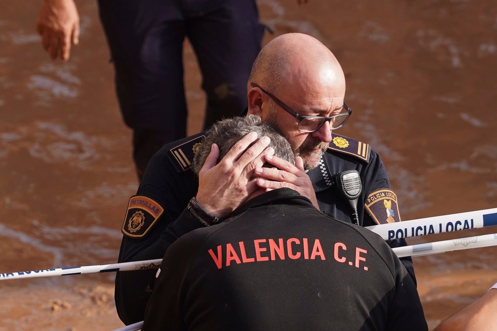 Members of the local police react to the news of one of their colleagues who died in the floods in Valencia, Spain, Thursday, Oct. 31, 2024. (AP Photo/Alberto Saiz)