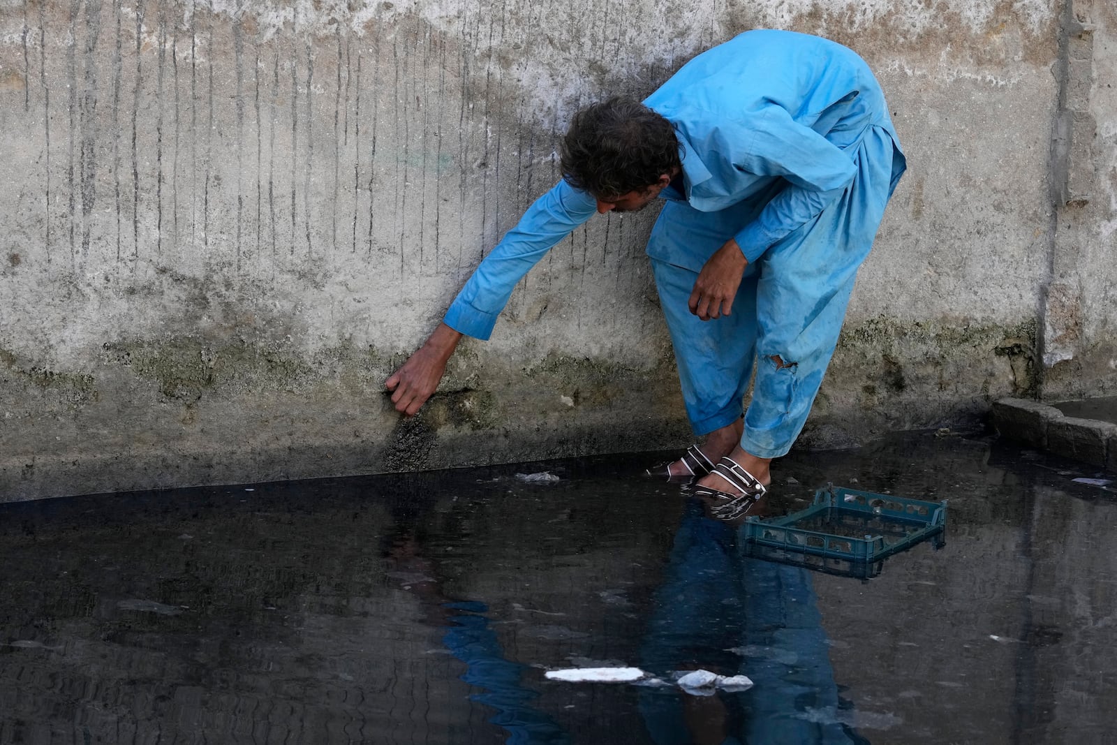 Amanullah shows a wall impacted by rising water in the compound of his home in a neighborhood of Gwadar, Pakistan, Tuesday, Jan. 14, 2025. (AP Photo/Anjum Naveed)