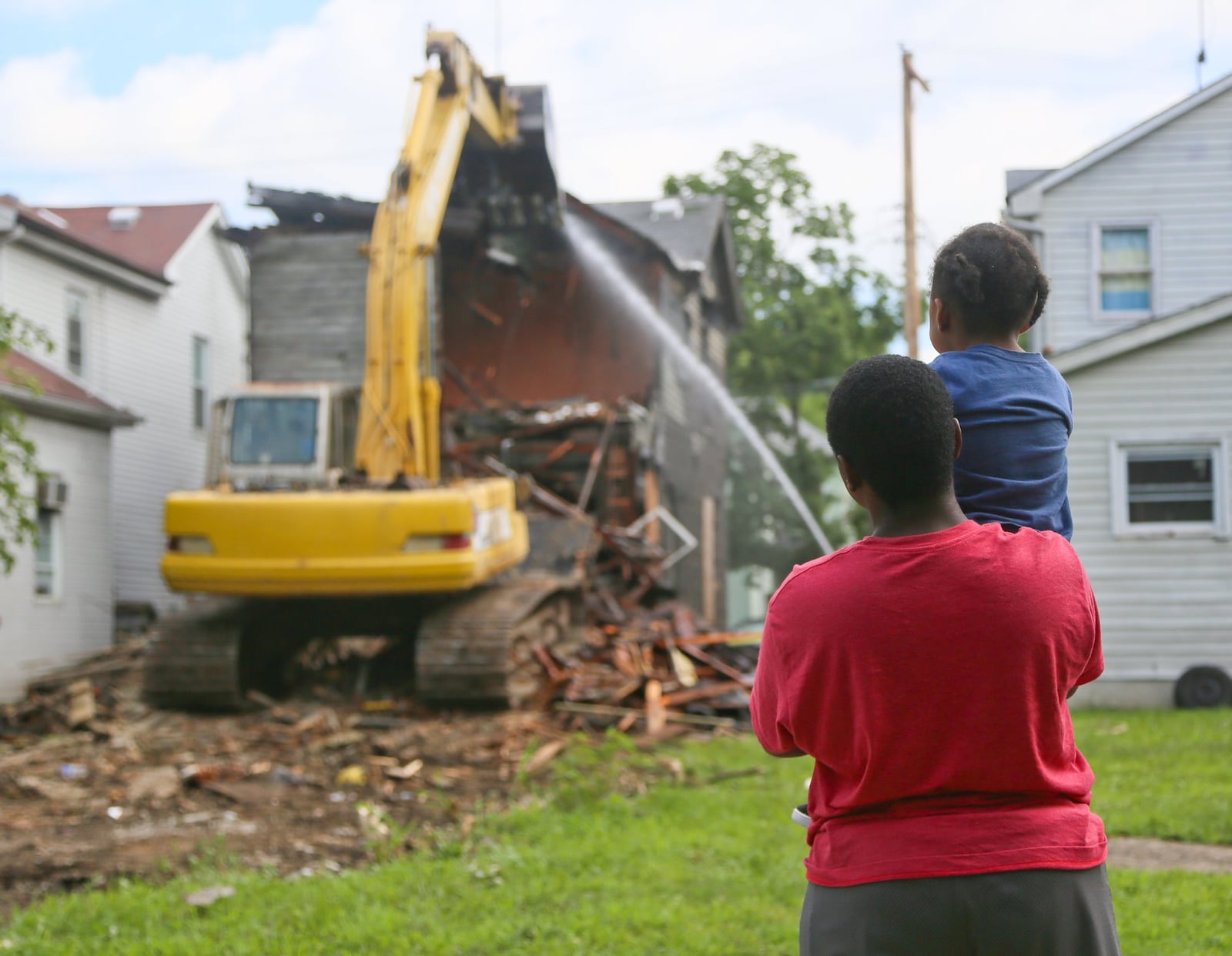 Kahmi Pryor, 13, and his younger brother Kalani, 3, watch as demolition crews tear down a house at 335 Hanover Street, Friday, July 15, 2016. The state and federal governments have just awarded Butler county an additional $1.7 million in Hardest Hit funds to continue purging dilapidated properties. GREG LYNCH / STAFF