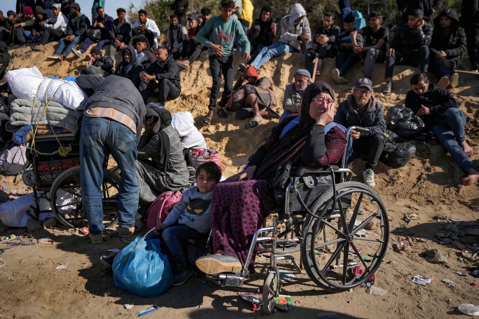 Displaced Palestinians gather with their belongings near a roadblock on the al Rashid Street, as they wait to return to their homes in the northern part of the Gaza Strip, Sunday, Jan. 26, 2025, days after the ceasefire deal between Israel and Hamas came into effect. (AP Photo/Abdel Kareem Hana)