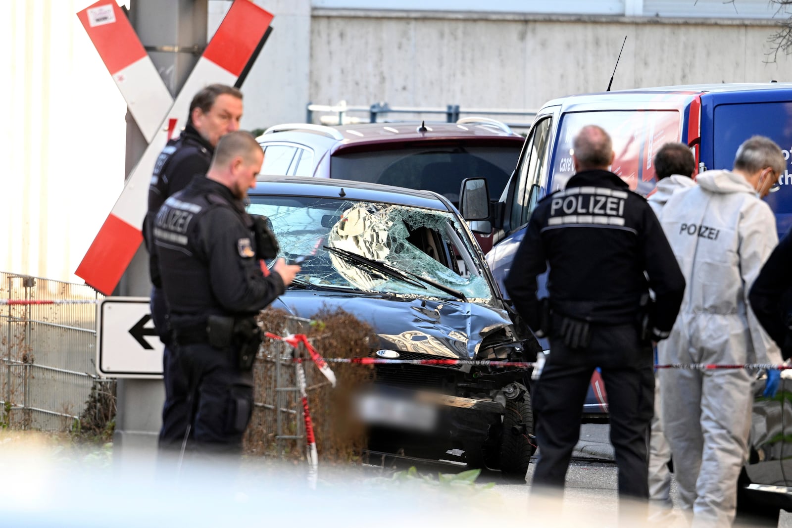 Police officers stand next to a damaged vehicle in the city center of Mannheim, Germany, Monday March 3, 2025, following an incident in which one person was killed and others injured when a car rammed into a crowd, German police said. (Boris Roessler/dpa via AP)