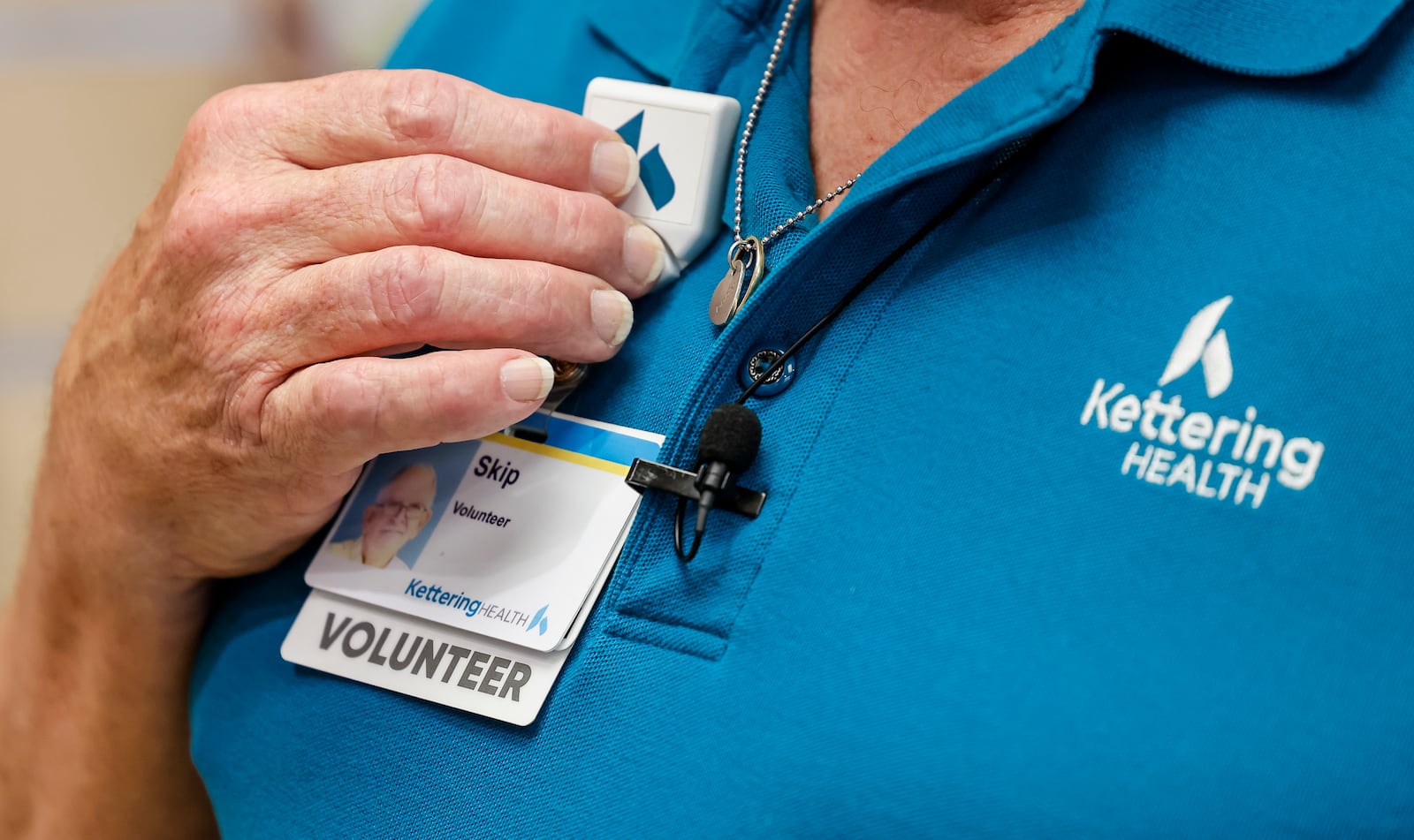 Skip Batten carries on his late wife's legacy by volunteering at the Wishing Well Gift Shop at Kettering Health Hamilton. Batten wears the badge holder his wife, Marie, used when she volunteered at the gift shop. NICK GRAHAM/STAFF