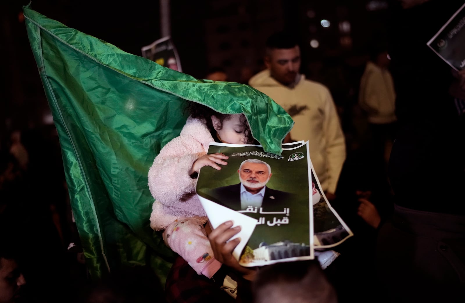 A Palestinian child holds a posters with the photo of late Hamas leader Ismail Haniyeh as they wait for the arrival of the released Palestinian prisoners, in the West Bank city of Beitunia, on Sunday, Jan. 19, 2025. (AP Photo/Leo Correa)