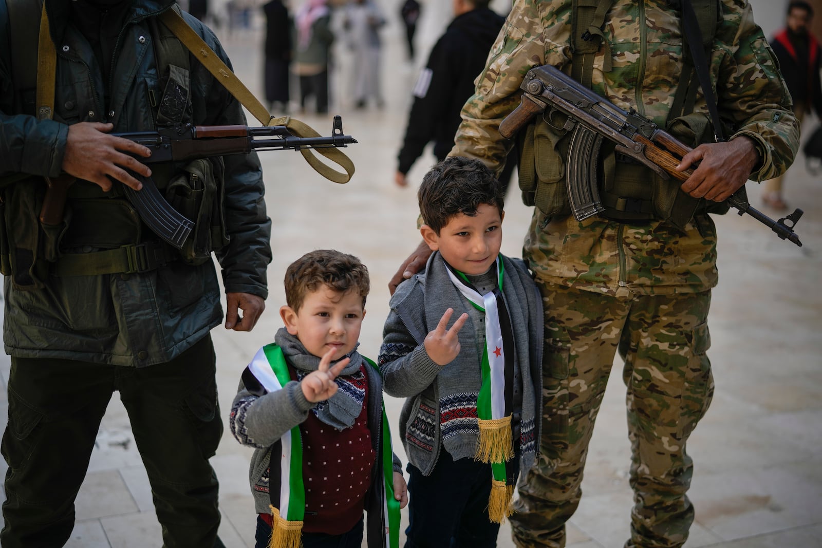 Two boys have their picture taken posing with Syrian fighters at the Umayyad Mosque ahead of Friday prayers in Damascus, Syria, Friday Dec. 20, 2024. 2024.(AP Photo/Leo Correa)