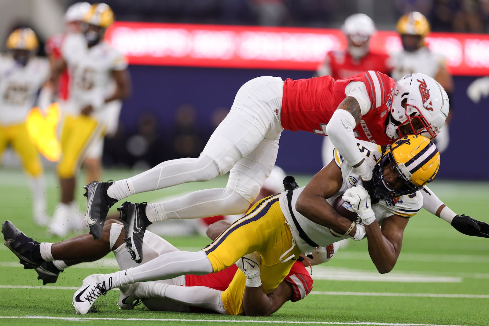 California wide receiver Tobias Merriweather, middle, is tackled by UNLV defensive backs Malik Chavis, top, and Jalen Catalon during the first half of the LA Bowl NCAA college football game Wednesday, Dec. 18, 2024, in Inglewood, Calif. (AP Photo/Ryan Sun)