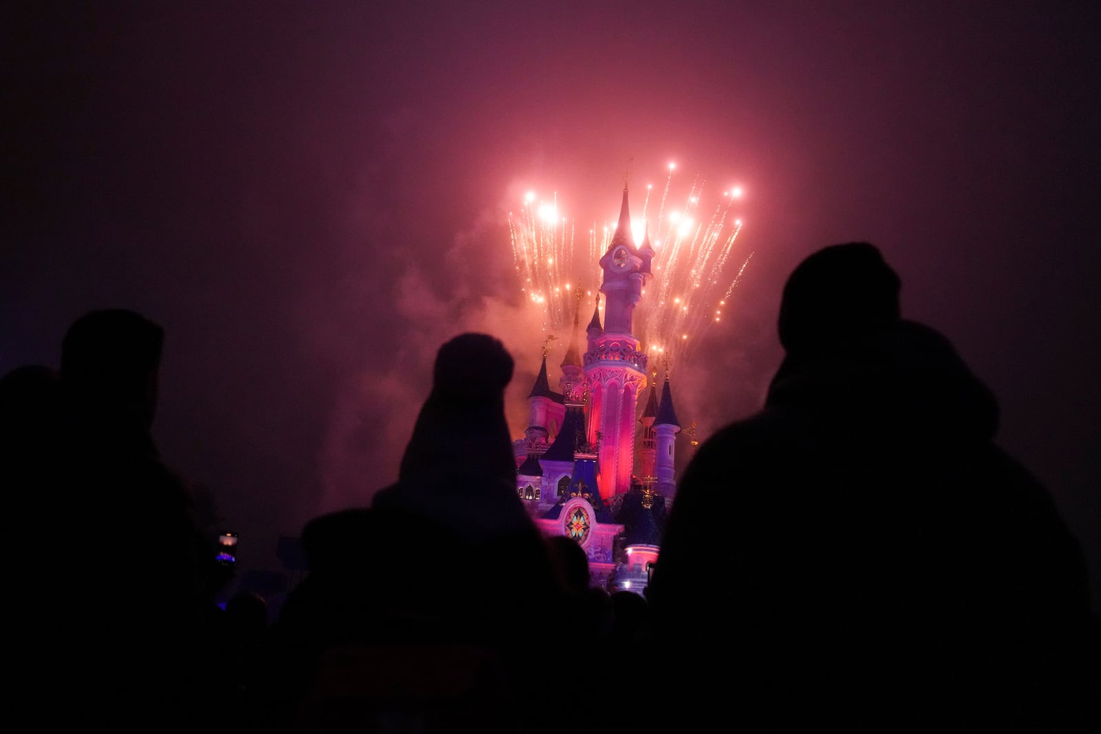 A light show is projected on the castle of Sleeping Beauty as fireworks explode in Disneyland, in Marne-la-Vallee, east of Paris, Friday Jan. 17, 2025. (AP Photo/Thibault Camus)