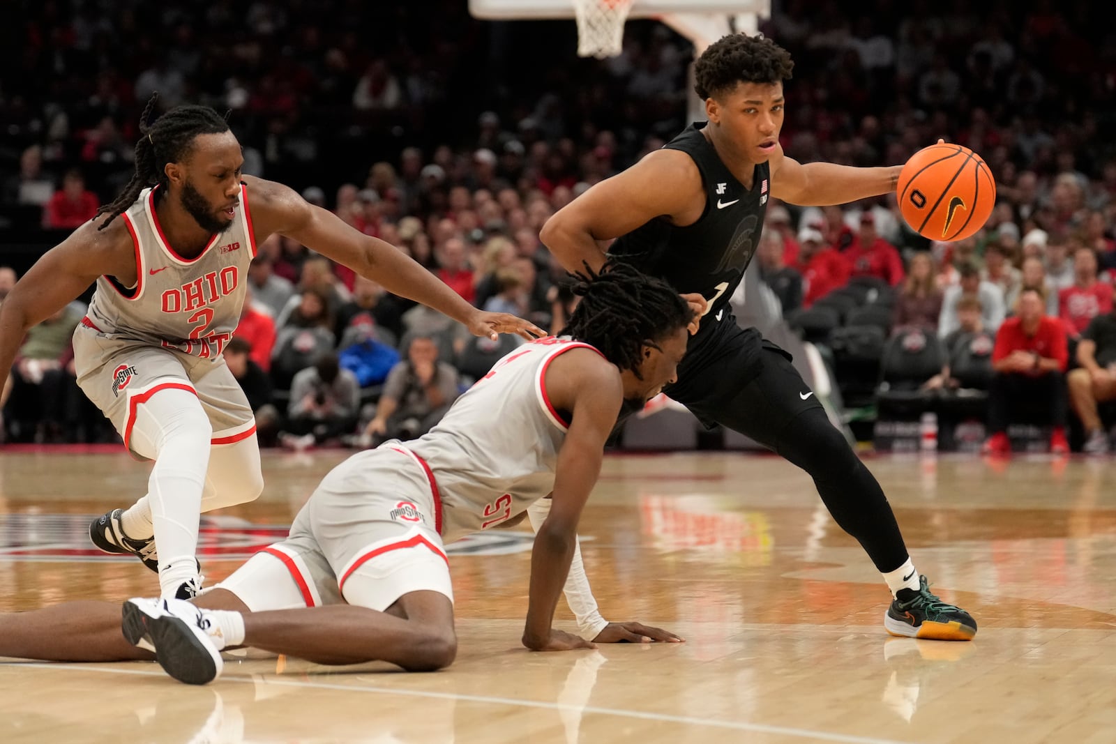 Michigan State guard Jeremy Fears Jr. (1) drives around Ohio State guard Bruce Thornton, left, and forward Aaron Bradshaw, center, in the second half of an NCAA college basketball game Friday, Jan. 3, 2025, in Columbus, Ohio. (AP Photo/Sue Ogrocki)