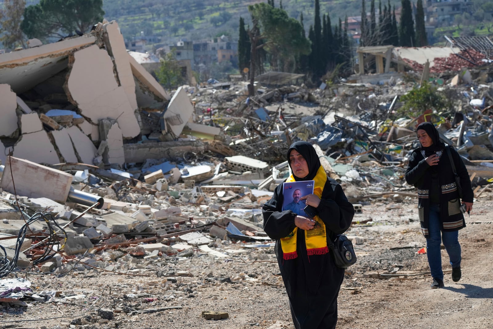 Lebanese citizens check the destruction in their village caused by the Israeli air and ground offensive, in the town of Kfar Kila, southern Lebanon, Tuesday, Feb. 18, 2025. (AP Photo/Hassan Ammar)