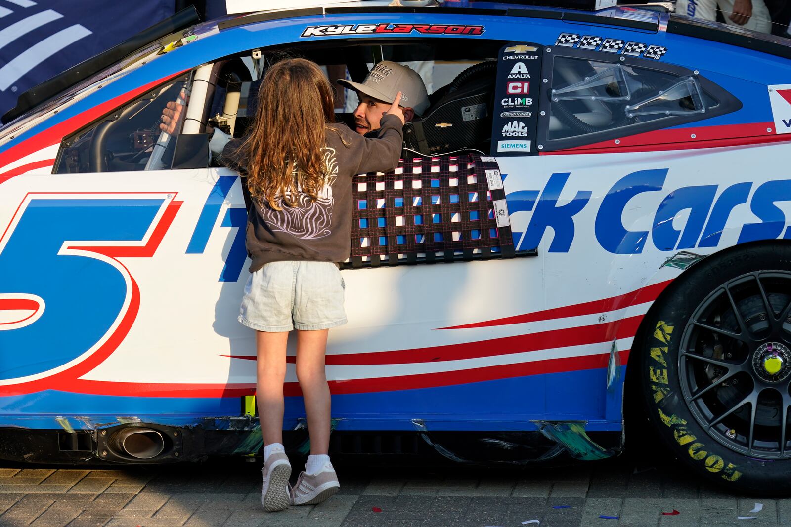 Kyle Larson talks with his daughter Audrey, 6, in Victory Lane after winning a NASCAR Cup Series auto race at Charlotte Motor Speedway in Concord, N.C., Sunday, Oct. 13, 2024. (AP Photo/Chuck Burton)