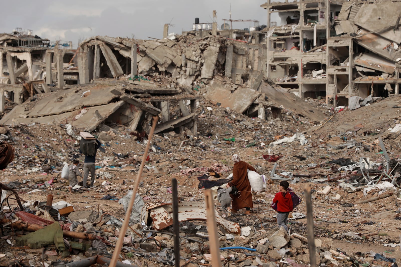 Palestinians walk on the rubble of destroyed houses, after the ceasefire deal between Israel and Hamas, in Gaza City, Gaza Strip, Friday, Jan. 24, 2025. (AP Photo/Abed Hajjar)