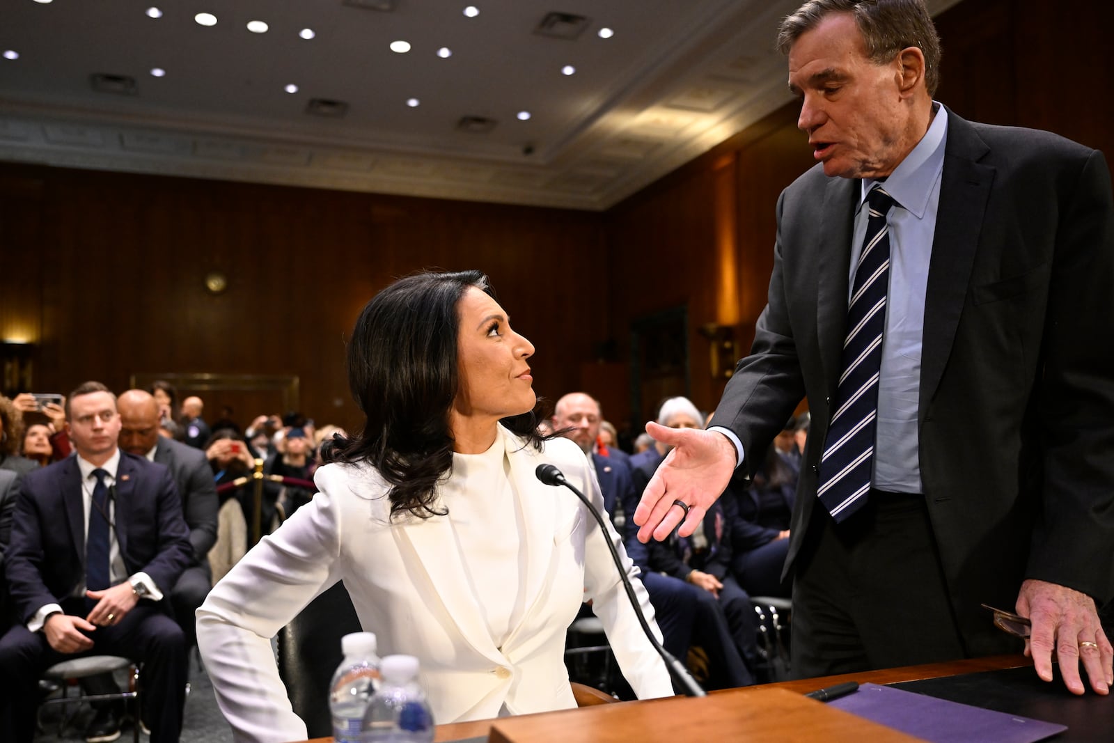 Former Rep. Tulsi Gabbard, President Donald Trump's nominee to be the Director of National Intelligence, left, is greeted by Vice Chairman Sen. Mark Warner, D-Va., as she appears before the Senate Intelligence Committee for her confirmation hearing at the U.S. Capitol on Thursday, Jan. 30, 2025, in Washington. (AP Photo/John McDonnell)