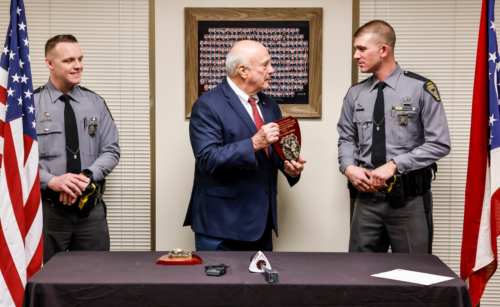 Butler County Prosecutor Mike Gmoser, middle, presented the annual Meritorious Service Award to Ohio State Highway Patrol Troopers Dominic O'Neill, left, and Justin Adleta, right, Friday, March 8, 2024 at his office in Hamilton. Adleta and O'Neill initiated a traffic stop that turned into a pursuit and eventual capture of four escapees from a Missouri Detention Center in January of 2023. NICK GRAHAM/STAFF