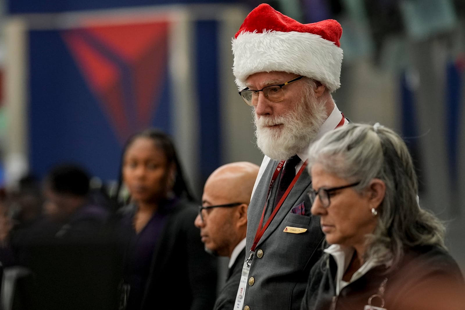 Delta Airlines employee Stanley Davis helps customers as people travel through Hartsfield-Jackson Atlanta International Airport, Friday, Dec. 20, 2024, in Atlanta. (AP Photo/Mike Stewart)