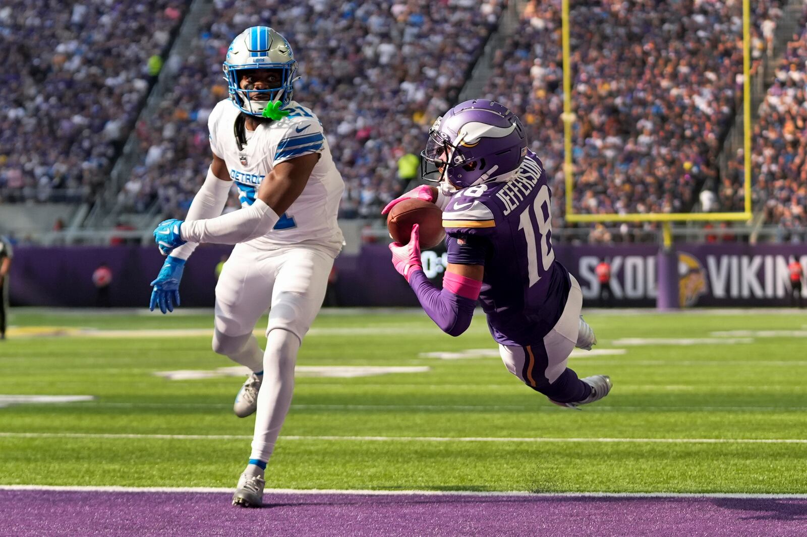 Minnesota Vikings wide receiver Justin Jefferson (18) catches 25-yard touchdown pass as Detroit Lions cornerback Amik Robertson (21) defends during the second half of an NFL football game Sunday, Oct. 20, 2024, in Minneapolis. (AP Photo/Abbie Parr)