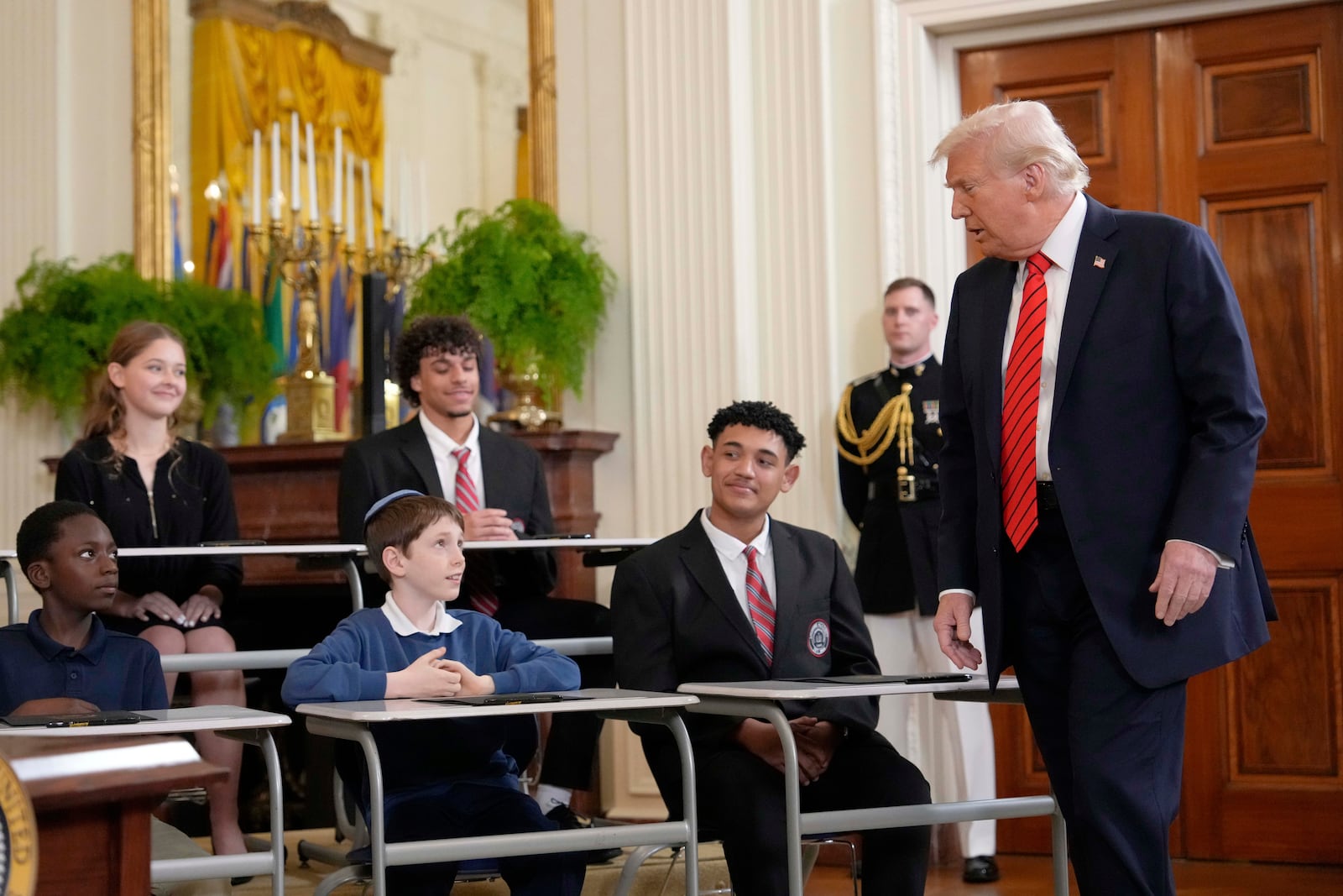 President Donald Trump addresses young people as he walks to sign an executive order in the East Room of the White House in Washington, Thursday, March 20, 2025. (AP Photo/Ben Curtis)