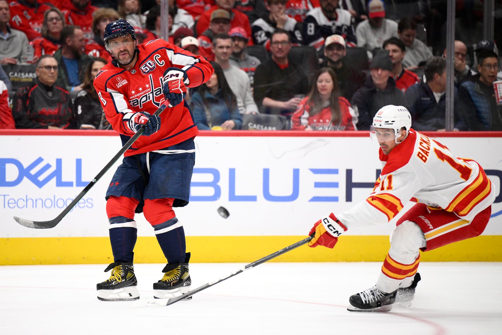 Washington Capitals left wing Alex Ovechkin passes the puck against Calgary Flames center Mikael Backlund during the second period of an NHL hockey game, Tuesday, Feb. 25, 2025, in Washington. (AP Photo/Nick Wass)