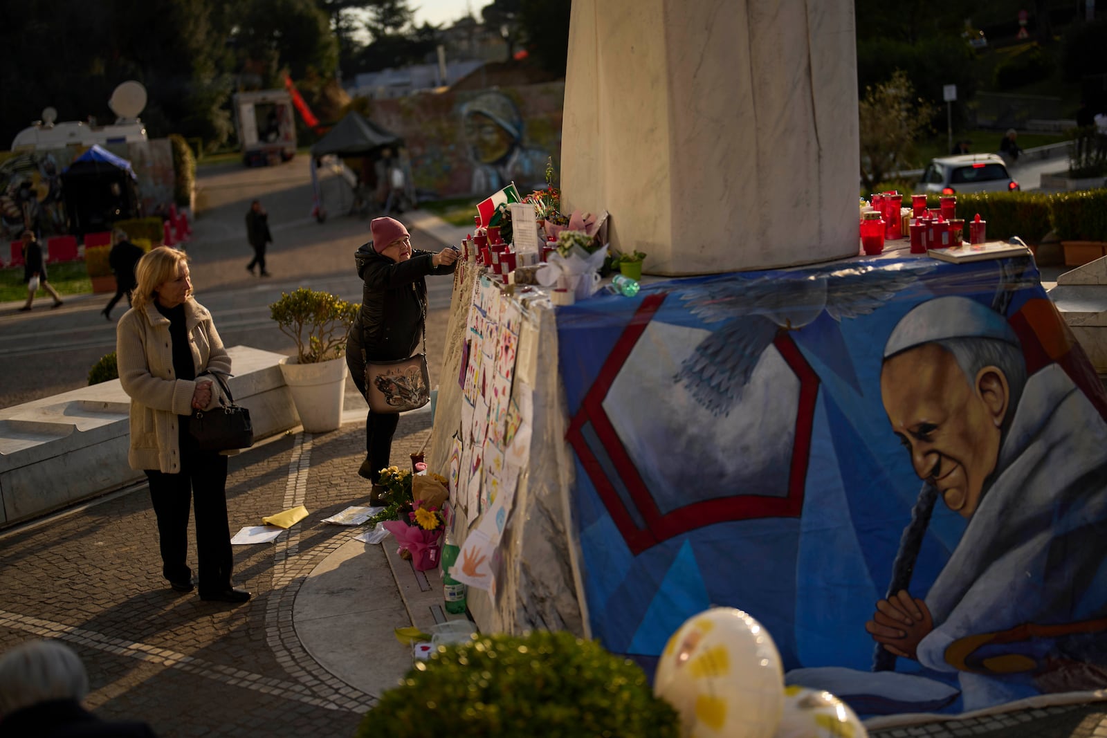 A woman places a Christian rosary at the statue of Pope John Paul II outside the Agostino Gemelli hospital in Rome, Thursday, March 6, 2025. (AP Photo/Francisco Seco)