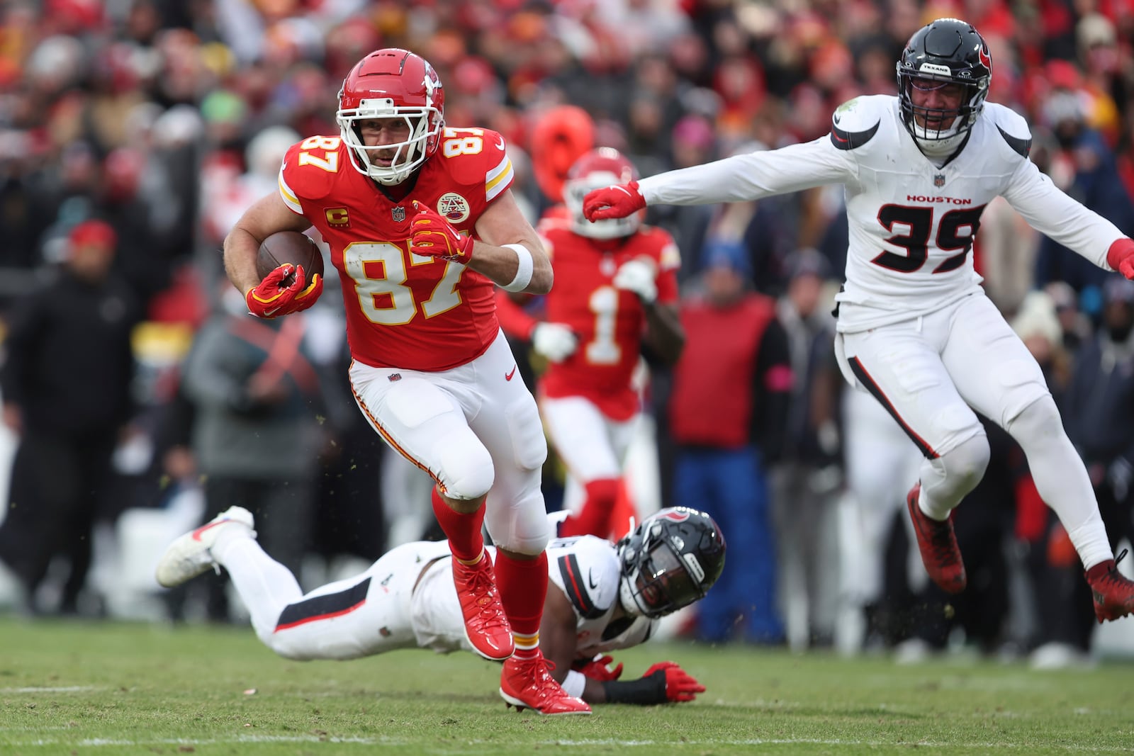 Kansas City Chiefs tight end Travis Kelce (87) runs with the ball as Houston Texans safety Calen Bullock (21) and linebacker Henry To'oTo'o (39) defend during the first half of an NFL football AFC divisional playoff game Saturday, Jan. 18, 2025, in Kansas City, Mo. (AP Photo/Travis Heying)