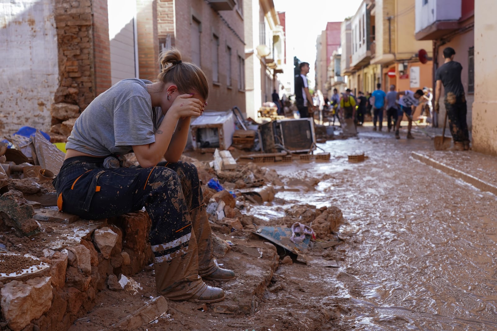 A woman rests as residents and volunteers clean up an area affected by floods in Paiporta, near Valencia, Spain, Friday, Nov. 1, 2024. (AP Photo/Alberto Saiz)