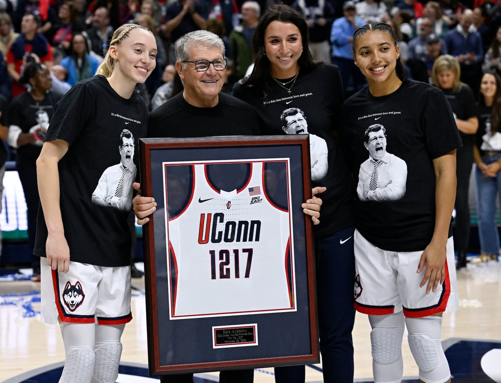 UConn head coach Geno Auriemma holds a jersey presented to him by players Paige Bueckers, left, Caroline Ducharme, and Azzi Fudd, right, as he is honored for the most wins in college basketball history, Wednesday, Nov. 20, 2024, in Storrs, Conn. (AP Photo/Jessica Hill)