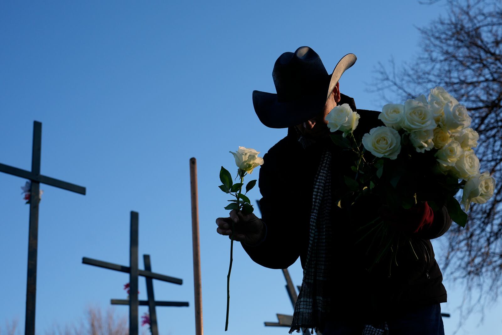 Roberto Marquez, of Dallas, places white roses at a memorial for the 67 victims of a midair collision between an Army helicopter and an American Airlines jet near the Ronald Reagan Washington National Airport, Saturday, Feb. 1, 2025, in Arlington, Va. (AP Photo/Carolyn Kaster)