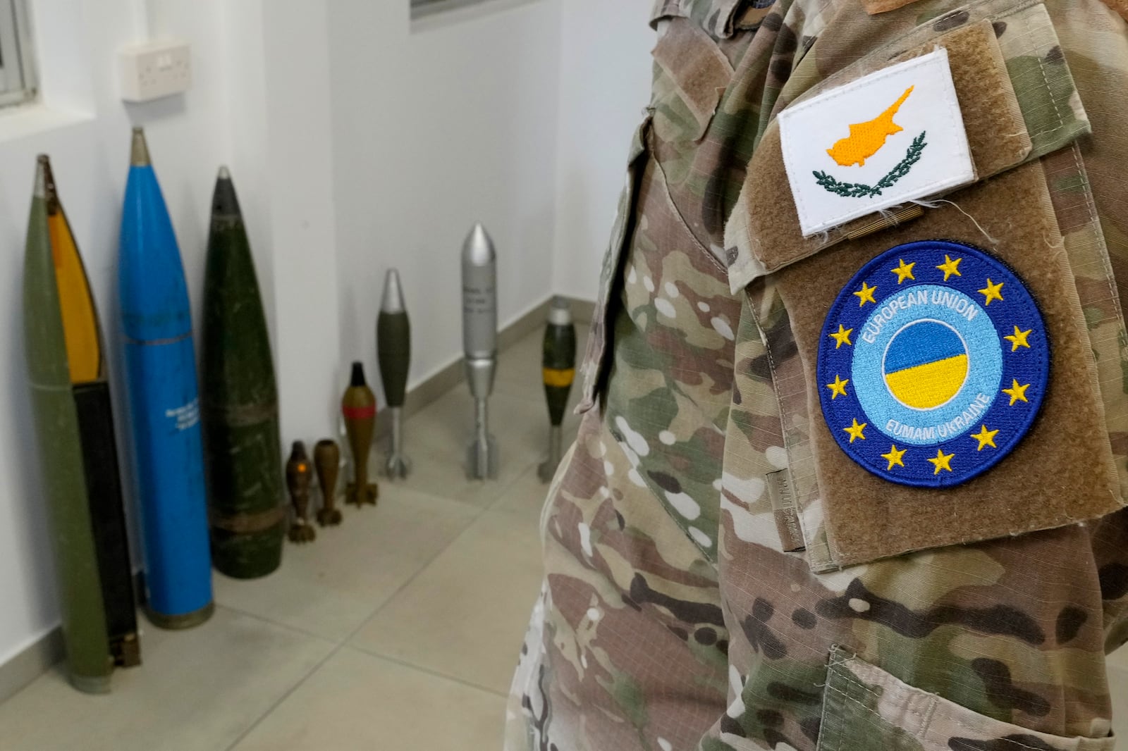 A Cypriot National Guardsman stands in front of a display of inert rockets, artillery shells and other munitions as part of a training course of Ukrainian personnel in the disposal of landmines and other explosive ordnance in Cyprus, at an army base, in Nicosia, Thursday, Nov. 14, 2024. (AP Photo/Petros Karadjias)