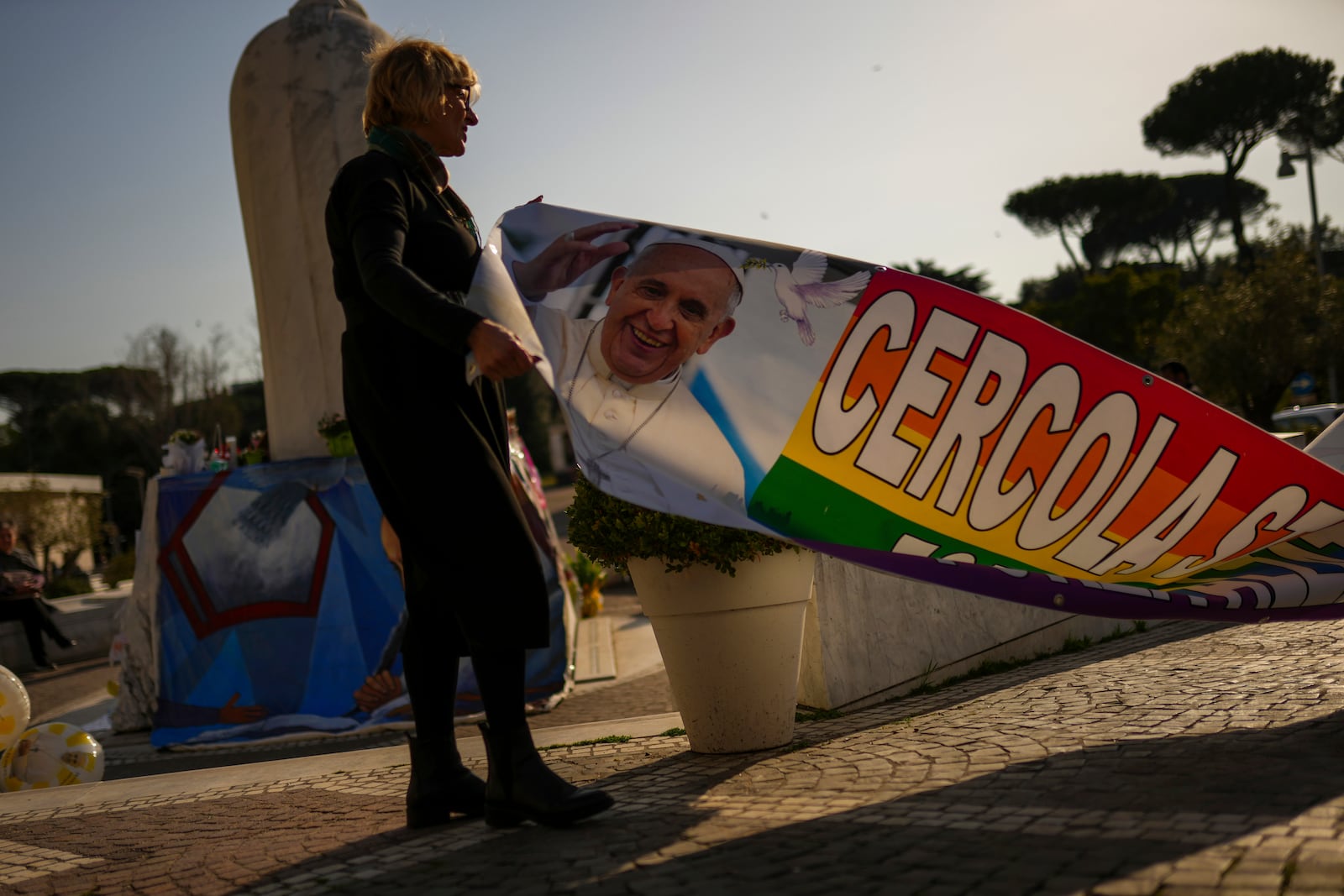 A woman holds a banner with a photograph of Pope Francis outside the Agostino Gemelli hospital in Rome, Thursday, March 6, 2025. (AP Photo/Francisco Seco)