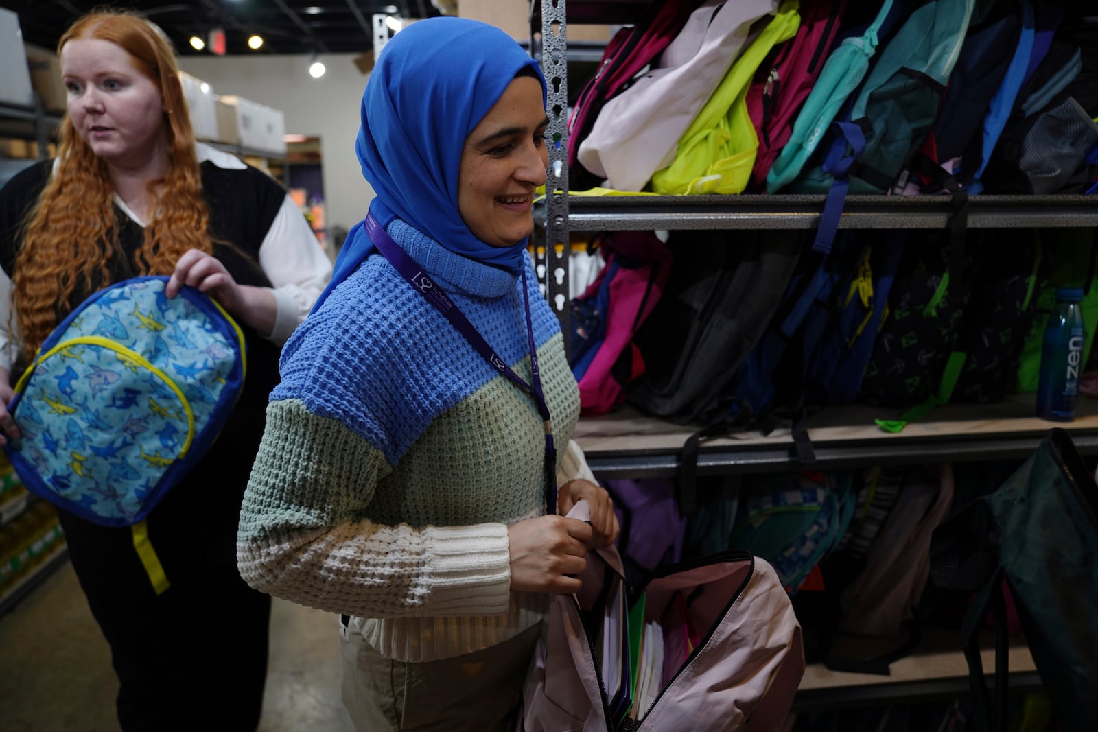 Alyssa Clifford, left, and Asma Baburi look through school backpacks stuffed with supplies at the Lutheran Social Services National Capital Area Resource Center where they both work, in Alexandria, Va., Thursday, March 6, 2025. (AP Photo/Jessie Wardarski)