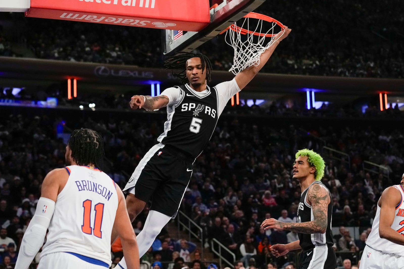 San Antonio Spurs' Stephon Castle, top, reacts after dunking the ball during the first half of an NBA basketball game against the New York Knicks, Wednesday, Dec. 25, 2024, in New York. (AP Photo/Seth Wenig)