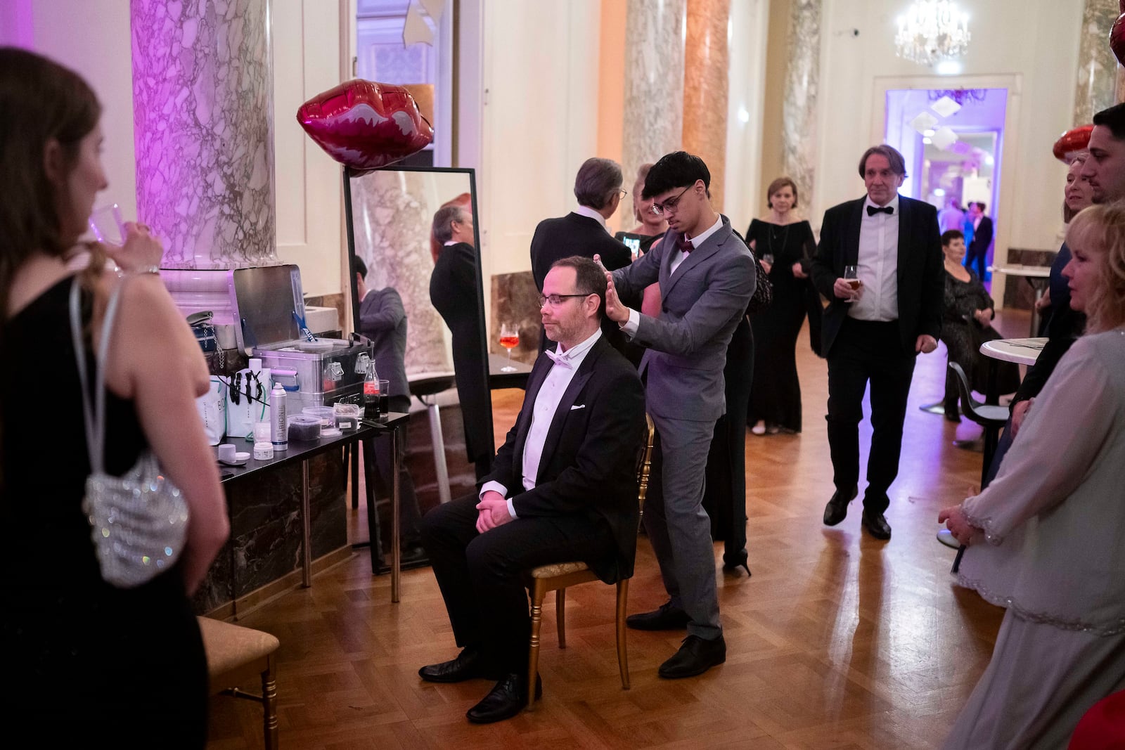 A hairdresser straightens a man's hair during the opening ceremony of the Lawyers' Ball in Vienna, Austria, Saturday, March 1, 2025. (AP Photo/Denes Erdos)