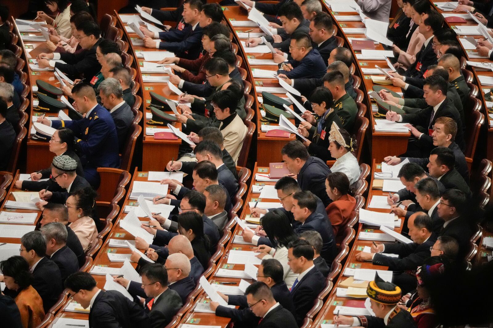 Delegates react during the opening session of the National People's Congress (NPC) at the Great Hall of the People in Beijing, China, Wednesday, March 5, 2025. (AP Photo/Vincent Thian)