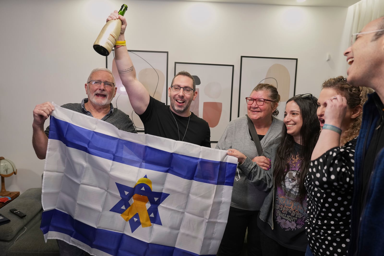 Family of Israeli hostage Ofer Kalderon react as they watch the broadcast of him being released from Hamas captivity, in Kfra Saba, southern Israel, Saturday Feb. 1, 2025, as part of the Israel-Hamas ceasefire deal. (AP Photo/Ariel Schalit)