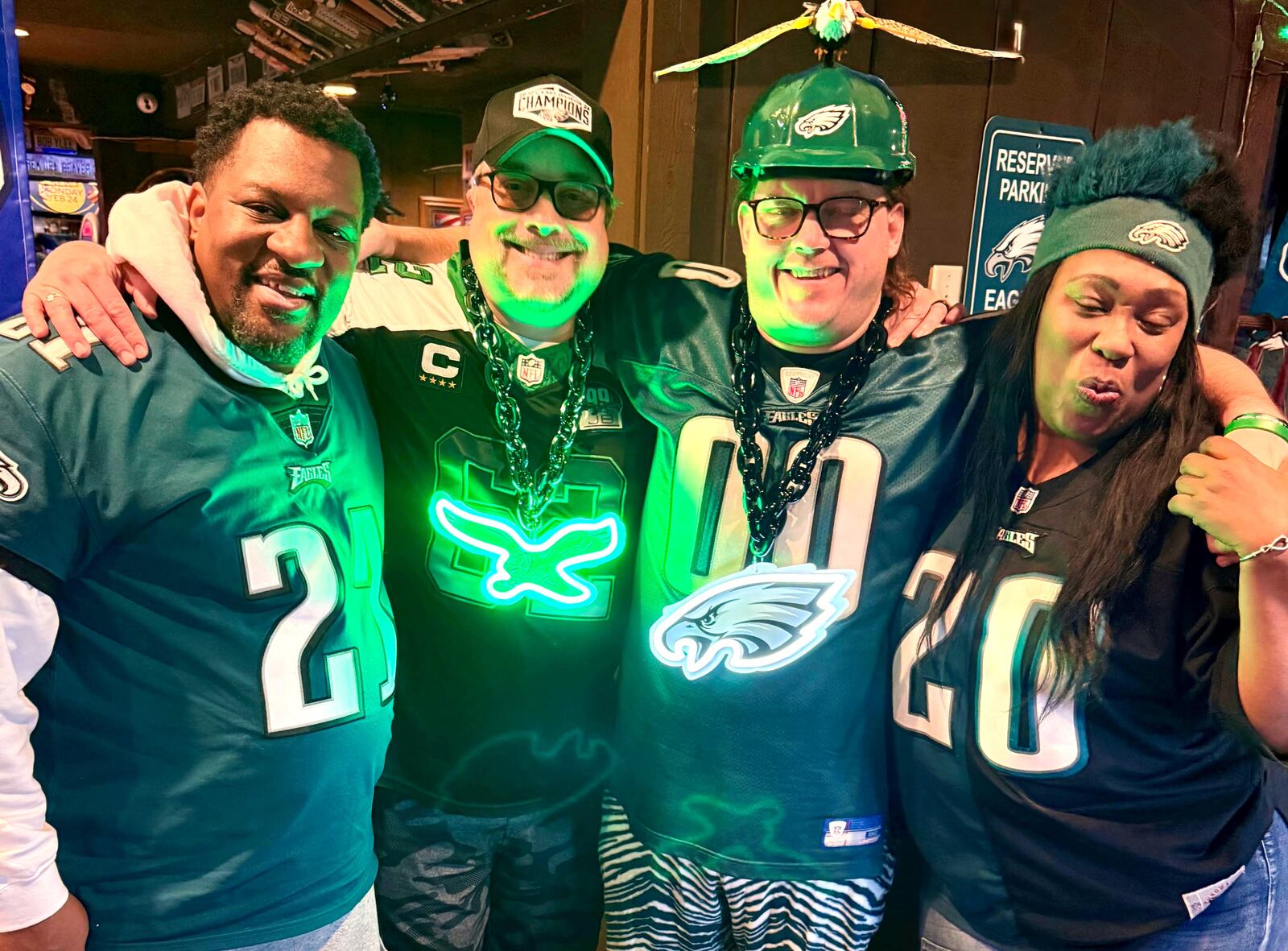 Fannie Woods, of Dayton, (right) poses for a photo with (left to right) James Watson, Jonathan Kuehnle and Back Porch Saloon manager Mike Solon at the West Chester Twp. business. Woods spends each game day at the saloon because of Midwest Eagles Nest, a fan gathering group founded by Gilmore and Solon in 2022.