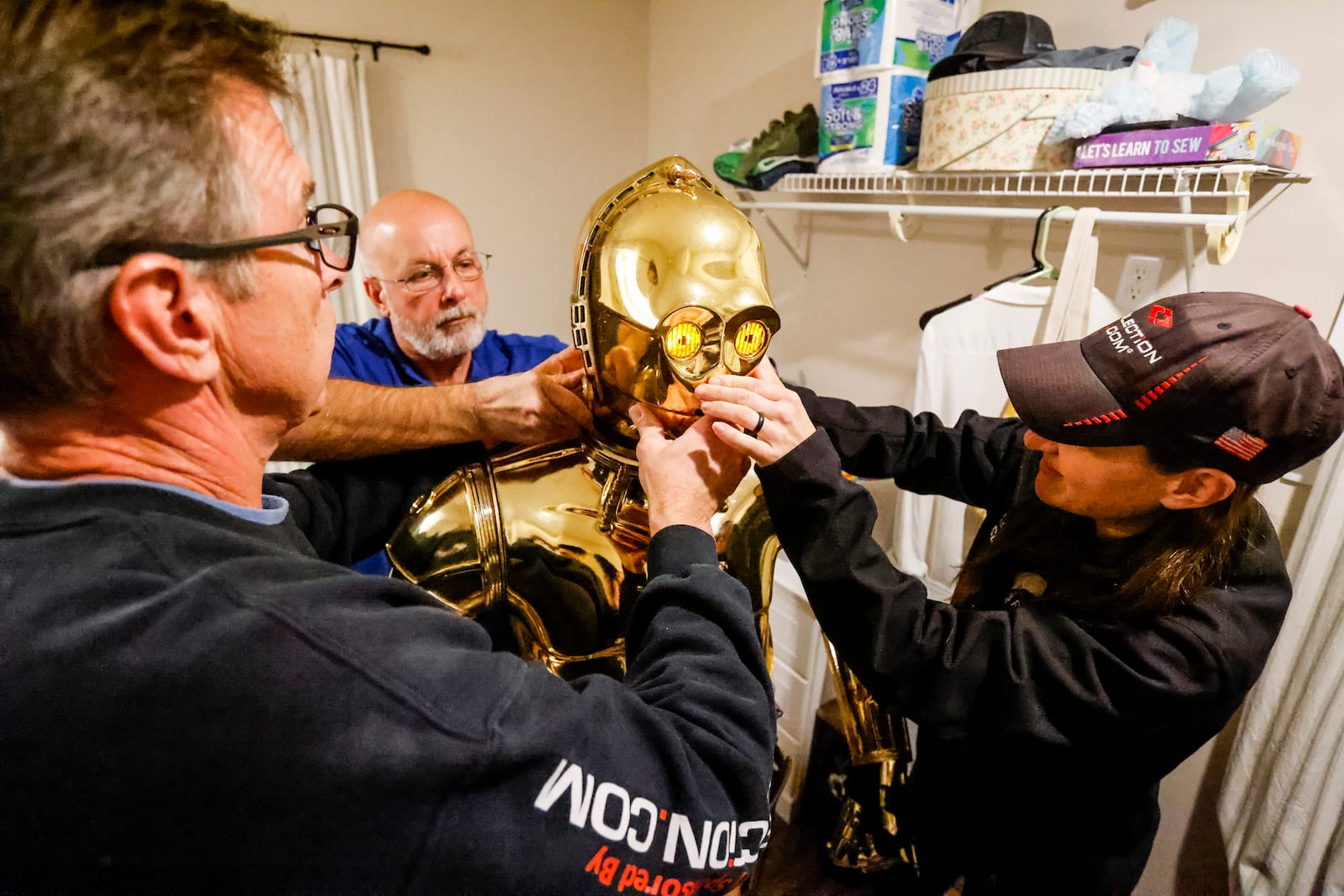 Middletown police officer Jim Lusk, John Hart, left, and Nicole Condrey, right, carefully fit the C3POcostume and the wires that operate the lights and microphone around Tim O’Sullivan before he surprises Porter Sowards, a 10-year-old who is battling brain cancer, with a visit from Star Wars charactersat his home Friday, Nov. 12, 2021 in Middletown. Team Fastax also presented Porter and his family with a Dreams of Fastrax certificate for a plane ride and indoor wind tunnel session. NICK GRAHAM / STAFF