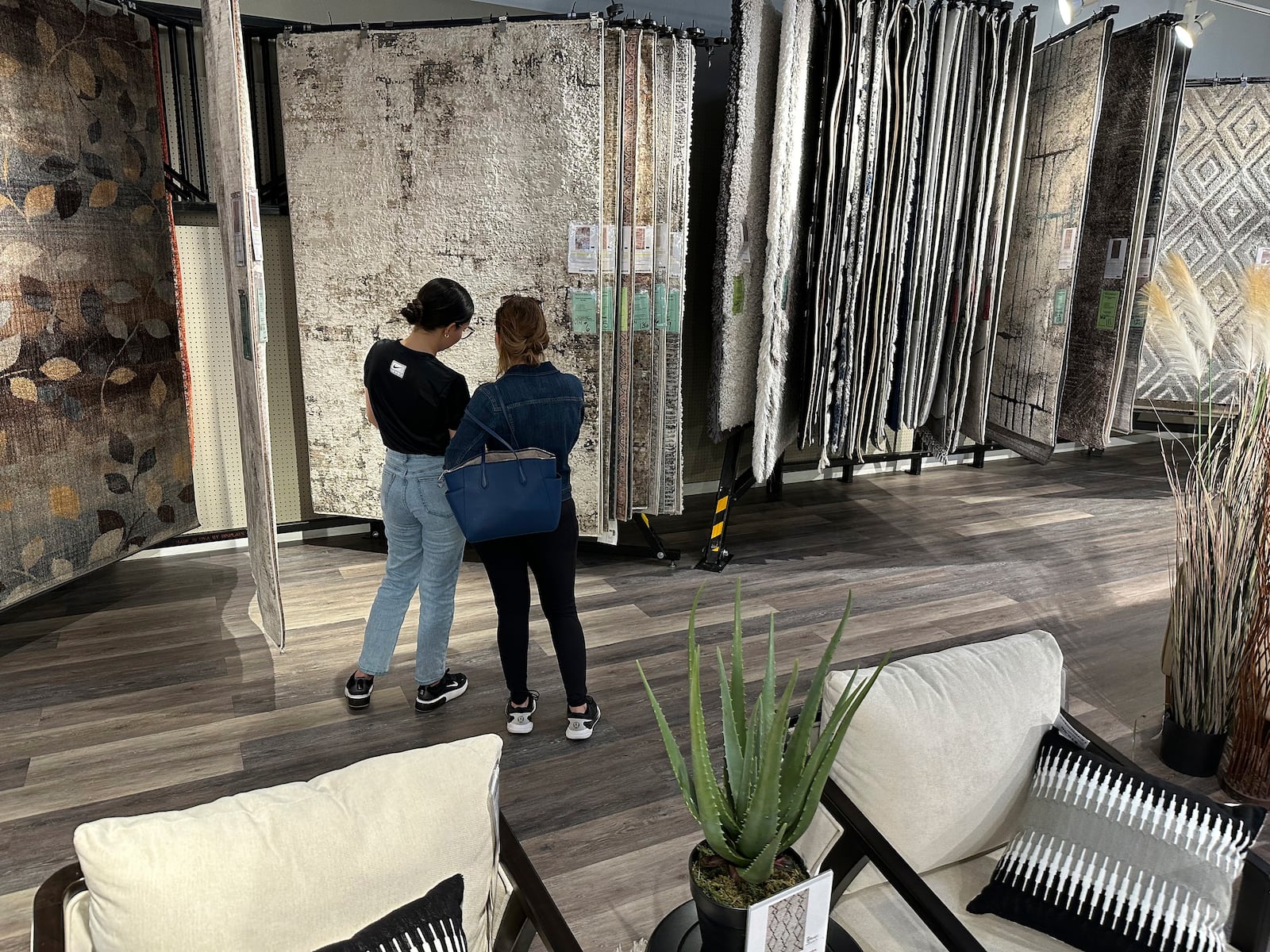 FILE - Shoppers consider rugs on display in a furniture store June 2, 2024, in Lone Tree, Colo. (AP Photo/David Zalubowski, File)