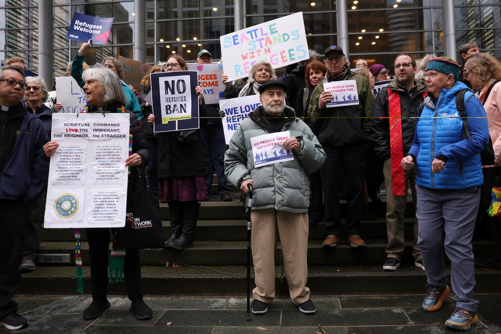 People hold signs as they gather outside the U.S. District Court after a federal judge blocked President Donald Trump's effort to halt the nation's refugee admissions system Tuesday, Feb. 25, 2025, in Seattle. (AP Photo/Ryan Sun)