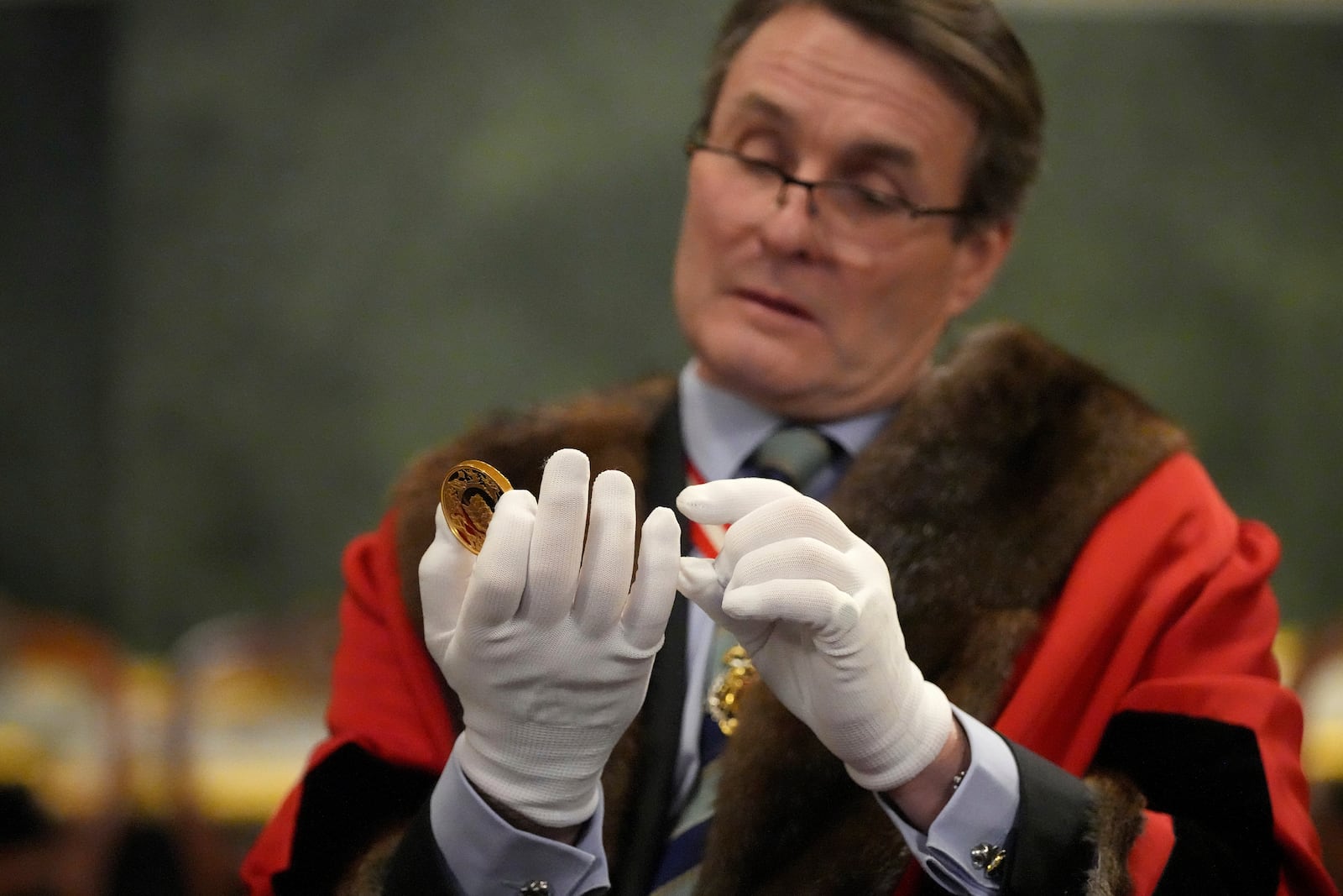 A warden inspects a commemorative gold coin during the "Trial of the Pyx,'' a ceremony that dates to the 12th Century in which coins are weighed in order to make certain they are up to standard, at the Goldsmiths' Hall in London, Tuesday, Feb. 11, 2025.(AP Photo/Frank Augstein)