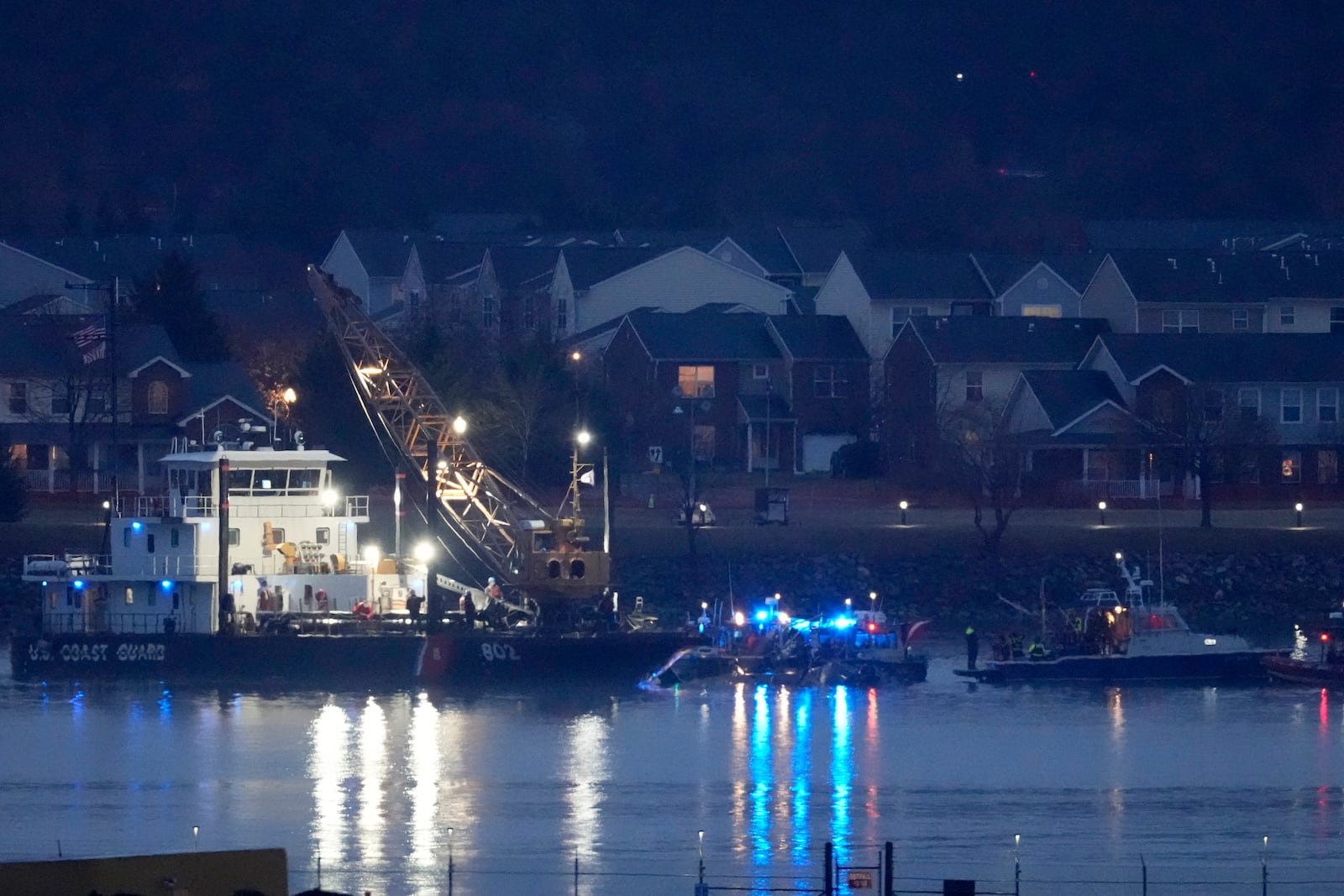 A Coast Guard vessel with a crane works near the wreckage of a Black Hawk helicopter in the Potomac River from Ronald Reagan Washington National Airport, Friday, Jan. 31, 2025, in Arlington, Va. (AP Photo/Alex Brandon)