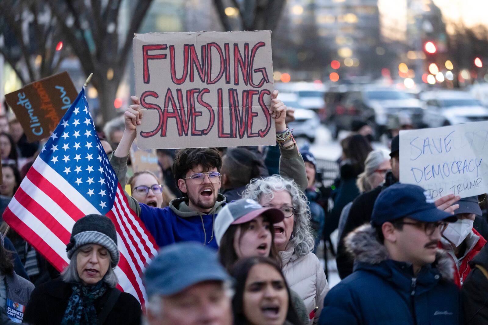 People protest against a funding freeze of federal grants and loans following a push from President Donald Trump to pause federal funding near to the White House in Washington, Tuesday, Jan. 28, 2025. (AP Photo/Ben Curtis)