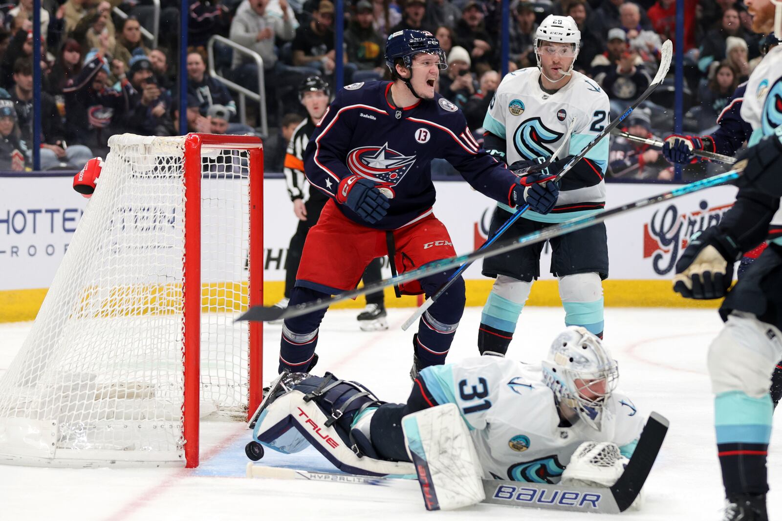 Columbus Blue Jackets forward Dmitri Voronkov, left, reacts to teammate defenseman Zach Werenski's goal past Seattle Kraken goalie Philipp Grubauer, bottom, and defenseman Vince Dunn during the second period of an NHL hockey game in Columbus, Ohio, Thursday, Jan. 9, 2025. (AP Photo/Paul Vernon)