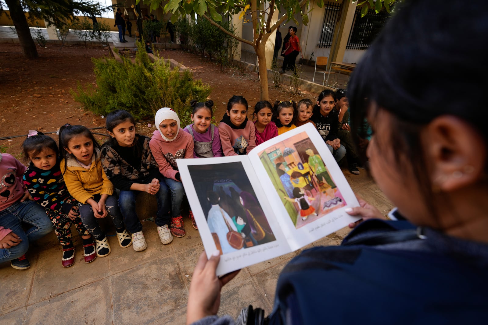 Displaced children, who fled Baalbek city and the nearby towns of Douris and Ain Bourday with their families amid the ongoing Hezbollah-Israel war, listen to a story at a school being used as a shelter, in Deir Al-Ahmar, east Lebanon, Thursday, Oct. 31, 2024. (AP Photo/Hassan Ammar)