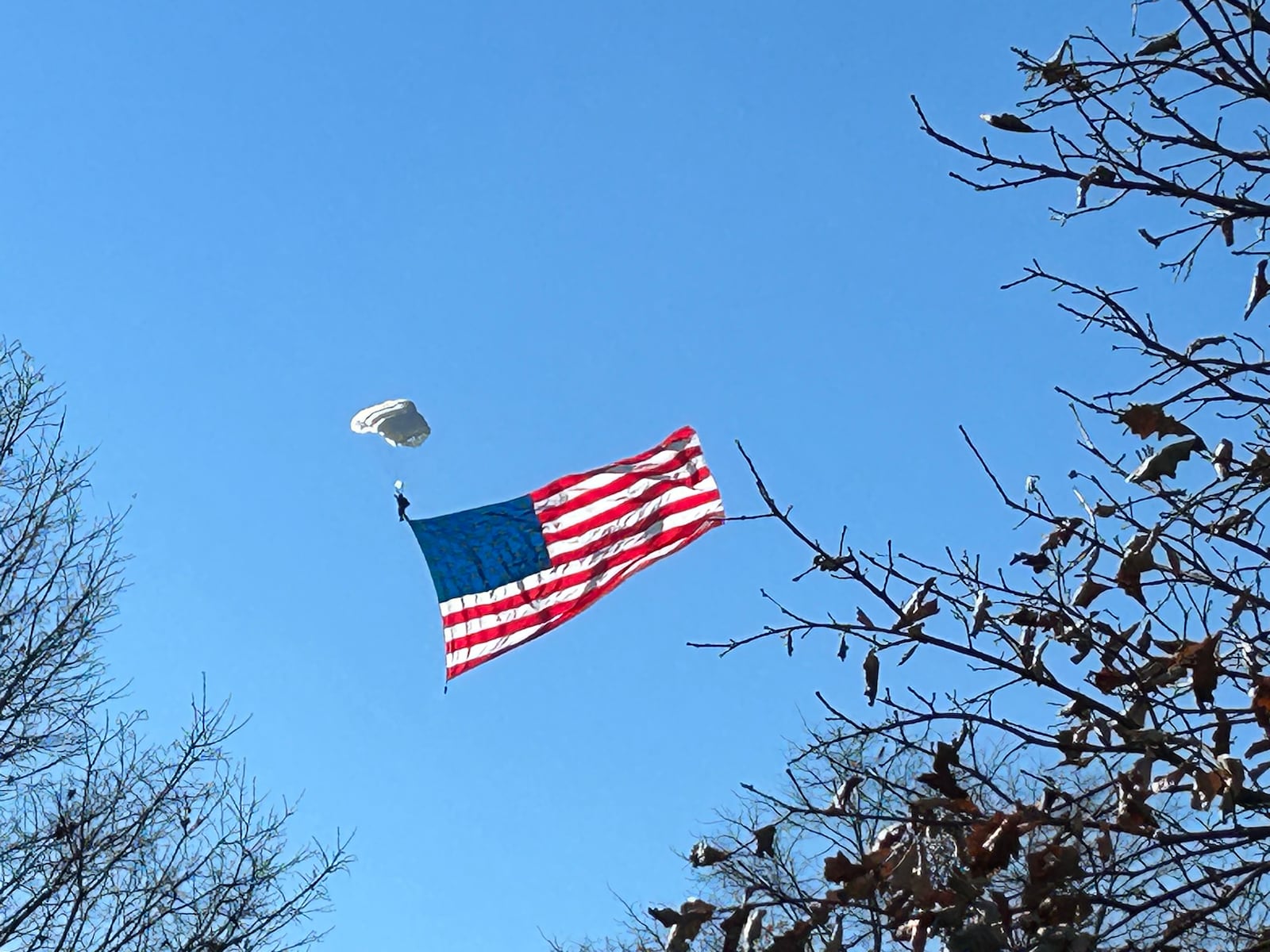 Ben Johnis, a member of Team Fastrax, a Middletown-based professional skydiving team, lands with the American flag Saturday morning at Woodside Cemetery as part of the city's Veterans Day ceremony. RICK McCRABB/STAFF