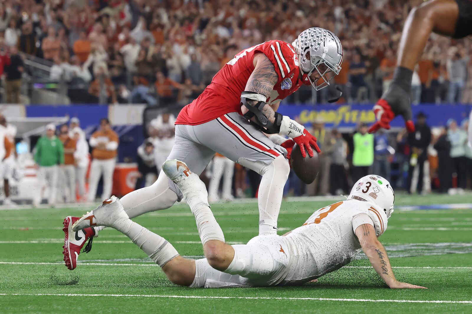 Ohio State defensive end Jack Sawyer, top, runs for a touchdown after recovering a fumble by Texas quarterback Quinn Ewers, bottom, during the second half of the Cotton Bowl College Football Playoff semifinal game, Friday, Jan. 10, 2025, in Arlington, Texas. (AP Photo/Gareth Patterson)