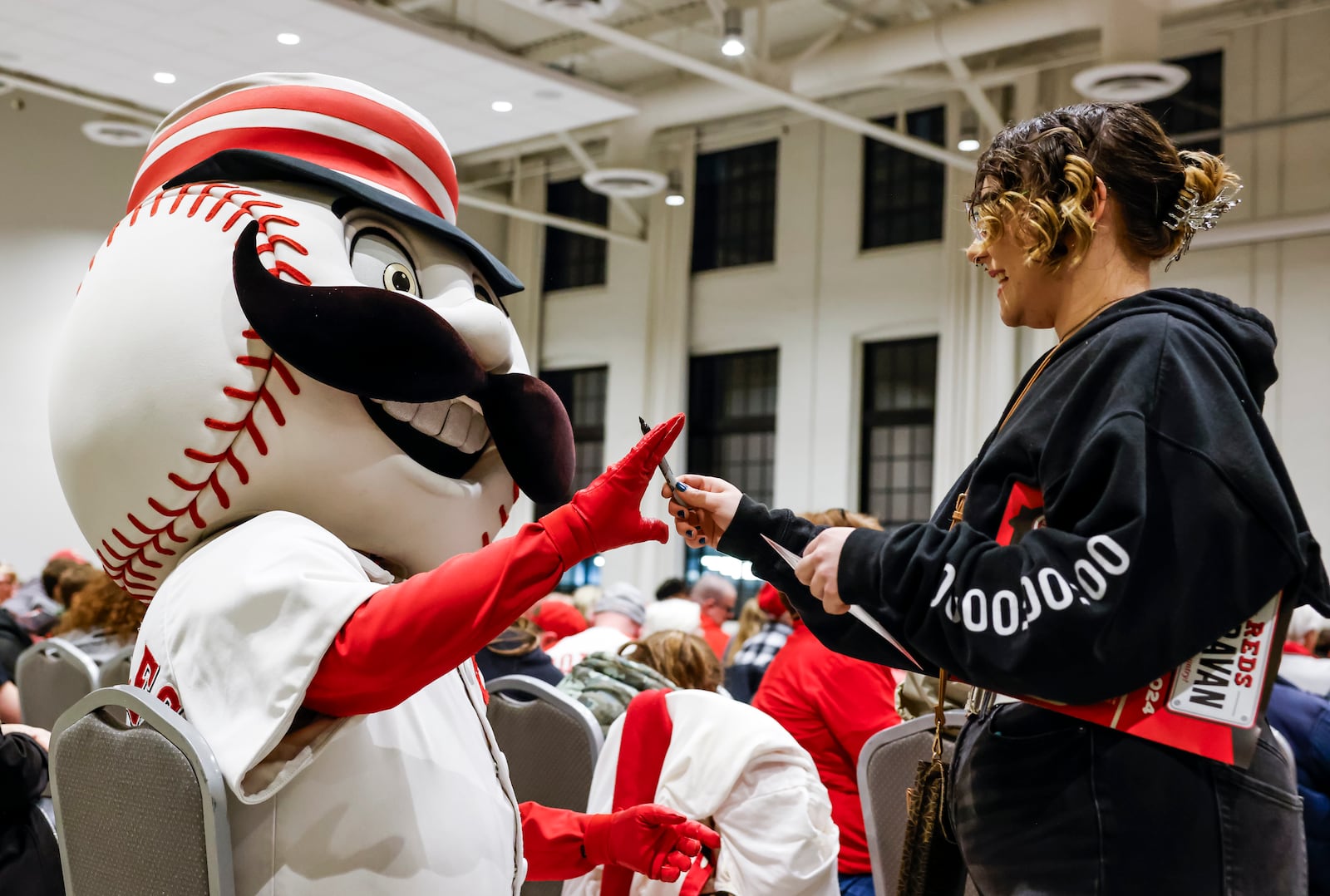 Mr. Redlegs signs autograph for Angelina Proffitt during the annual Reds Caravan at Spooky Nook Sports Champion Mill Monday, Jan. 22, 2024 in Hamilton. Fans were able to ask questions and get autographs during the event. The Central Tour featured broadcasters John Sadak and Brian Giesenschlag, pitcher Brent Suter, minor leaguers Jay Allen II, Chase Petty and Edwin Arroyo, Vice President of Player Development Shawn Pender, former player Corky Miller and mascot Mr. Redlegs. NICK GRAHAM/STAFF