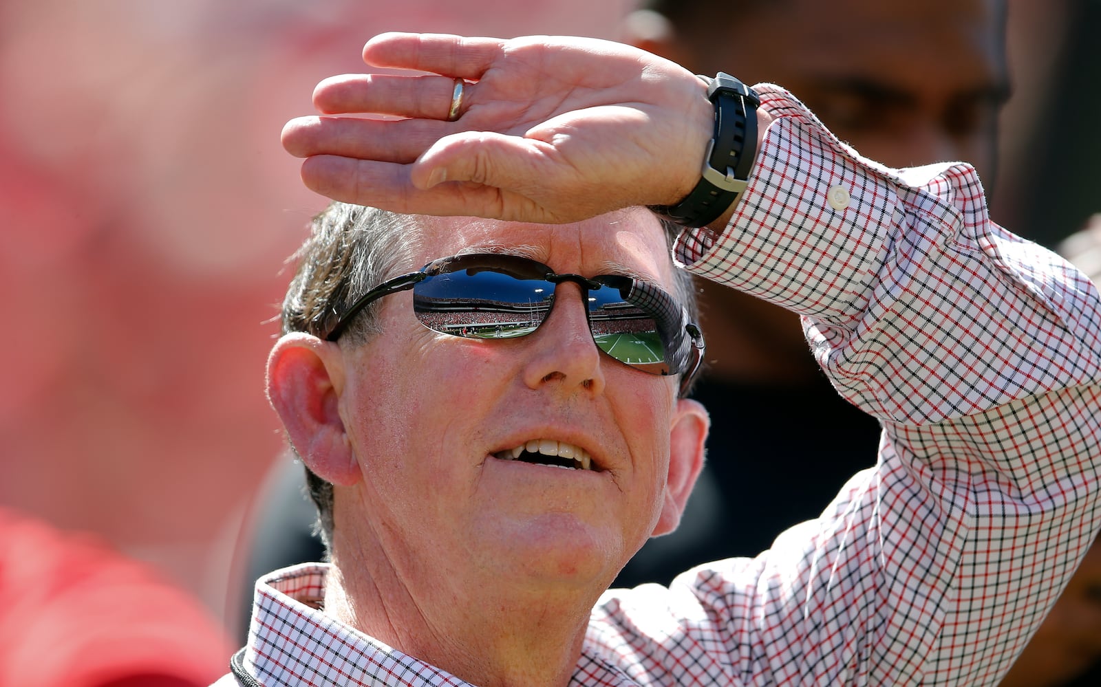 FILE - Sanford Stadium is reflected in Georgia athletic director Greg McGarity's sunglasses as he watches a pregame performance by rapper Ludacris before Georgia's spring intrasquad NCAA college football game Saturday, April 16, 2016, in Athens, Ga. (AP Photo/John Bazemore, File)