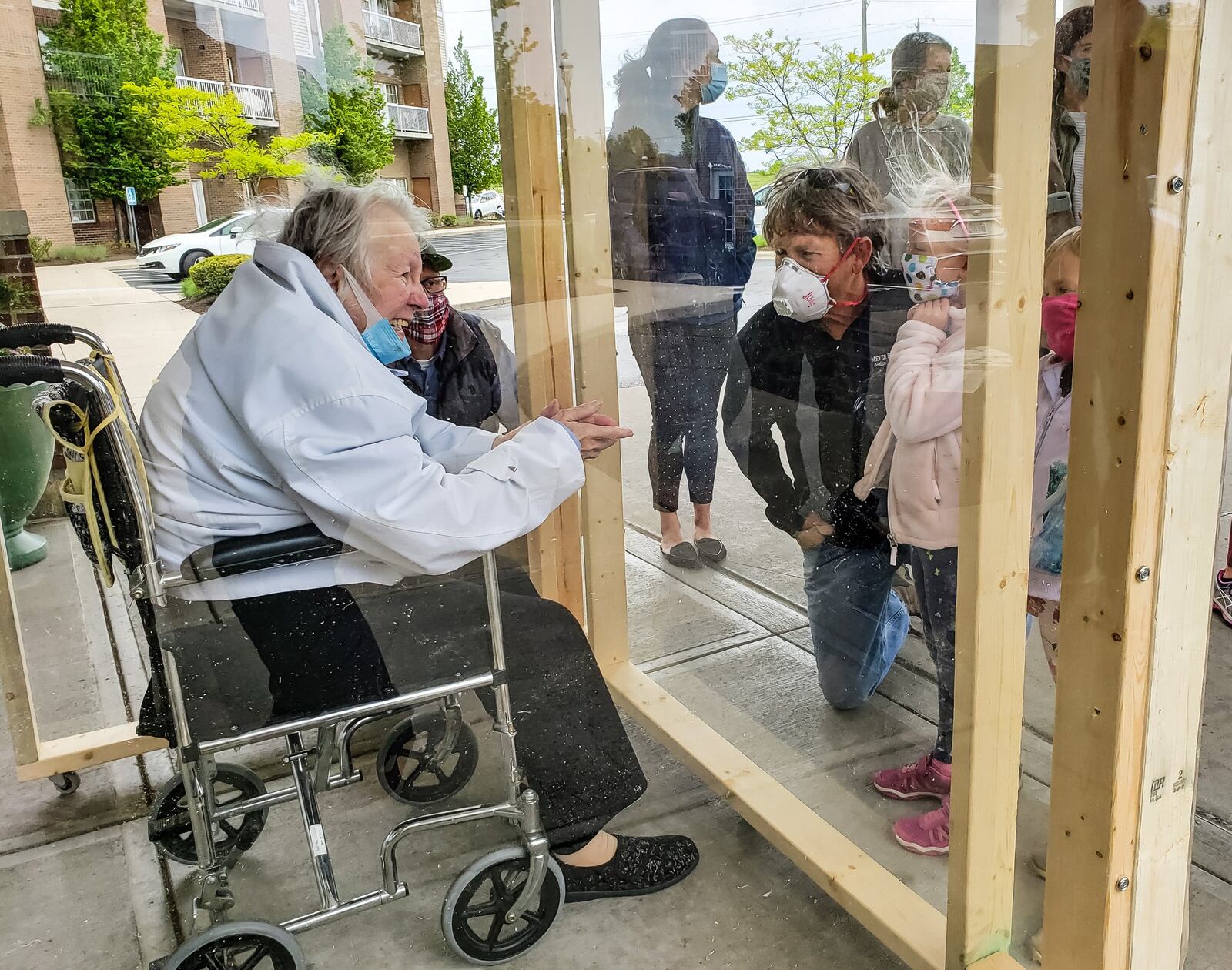 The family of Virginia “Ginny” Meyer, 95, was finally able to see her up closed thanks to a clear, protective box the family built to be placed outside Barrington of West Chester senior living facility Wednesday, May 13, 2020. Meyer’s children, grandchildren and great-grandchildren greeted her as she came out the door to see them up close for the first time in over two months due to the coronavirus pandemic. If they wanted to see her before they had to see her from her third floor balcony. NICK GRAHAM / STAFF